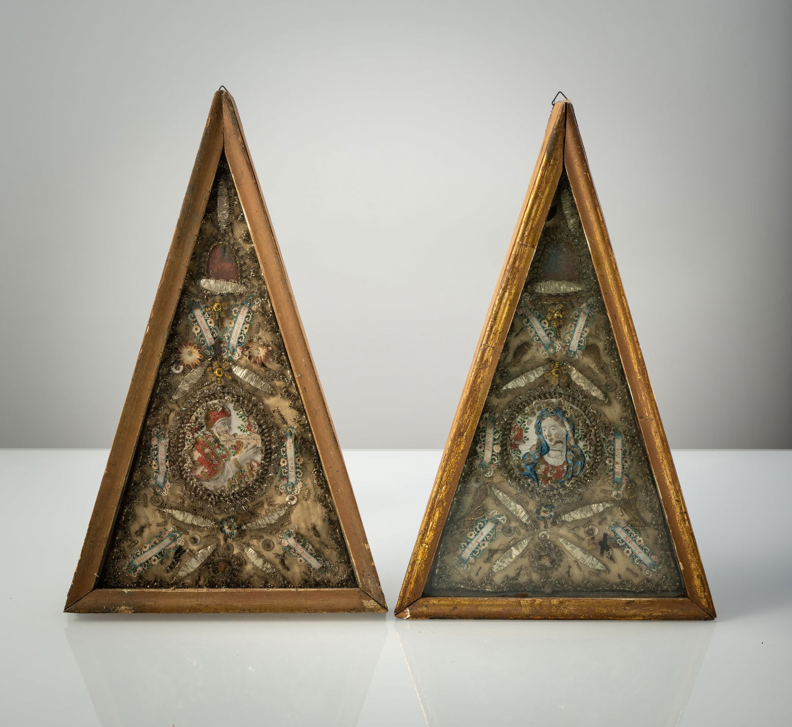 A PAIR OF MONASTERY WORKS: A PAIR OF MONASTERY WORKS 18th/19th century 40 x 25 cm Collage made of silver and gold wire, paper, fabric, and plaster medallions. Wooden frame. Damages due to agePaar Klosterarbeiten 18./19. Jhdt.