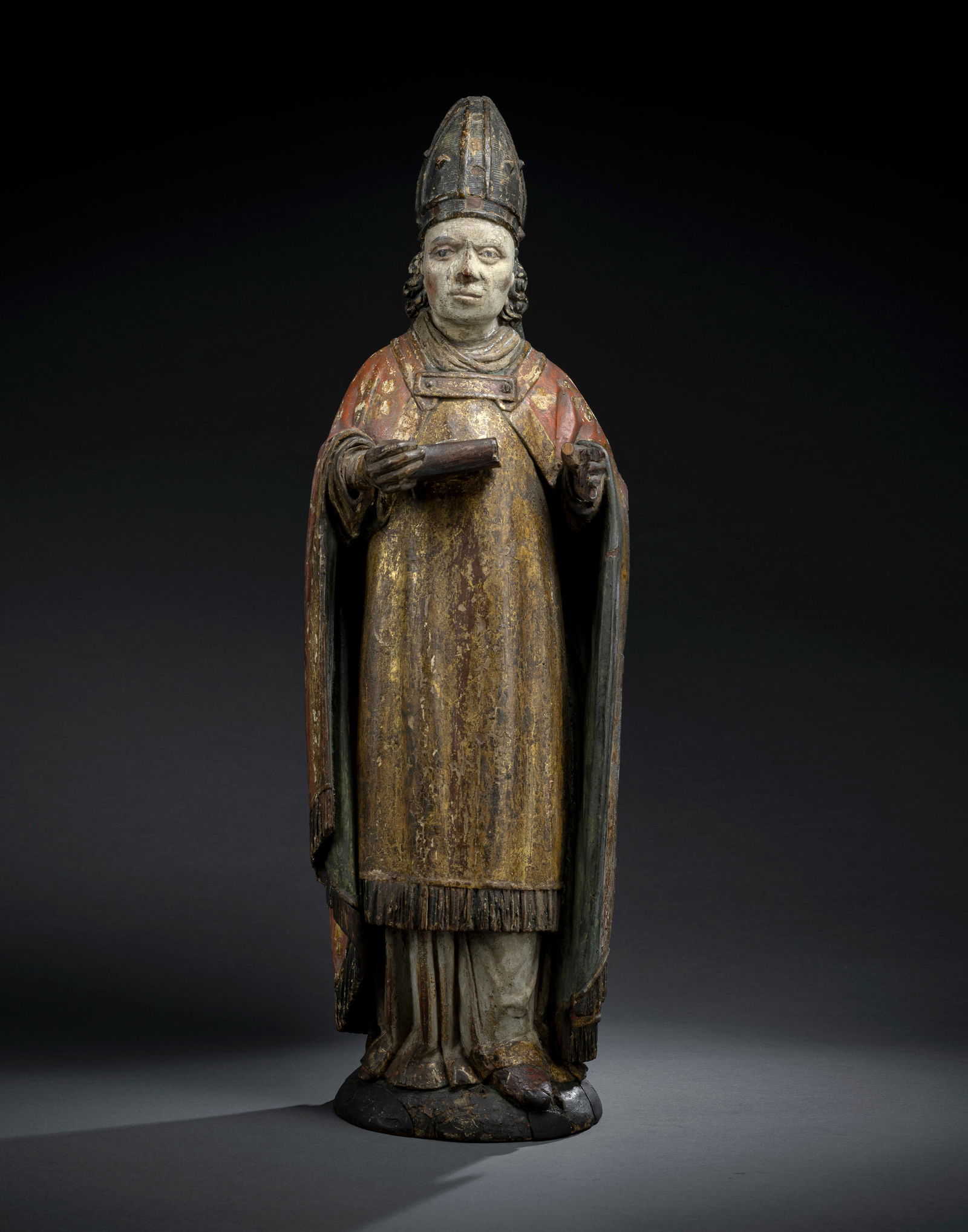 HOLY BISHOP: HOLY BISHOP Tyrol/South Tyrol, early 16th century H. 72 cm Swiss pine, carved in full round. Baroque polychromy with gold stamps and gold painting, partly rubbed. Inscribed on the bottom in black: