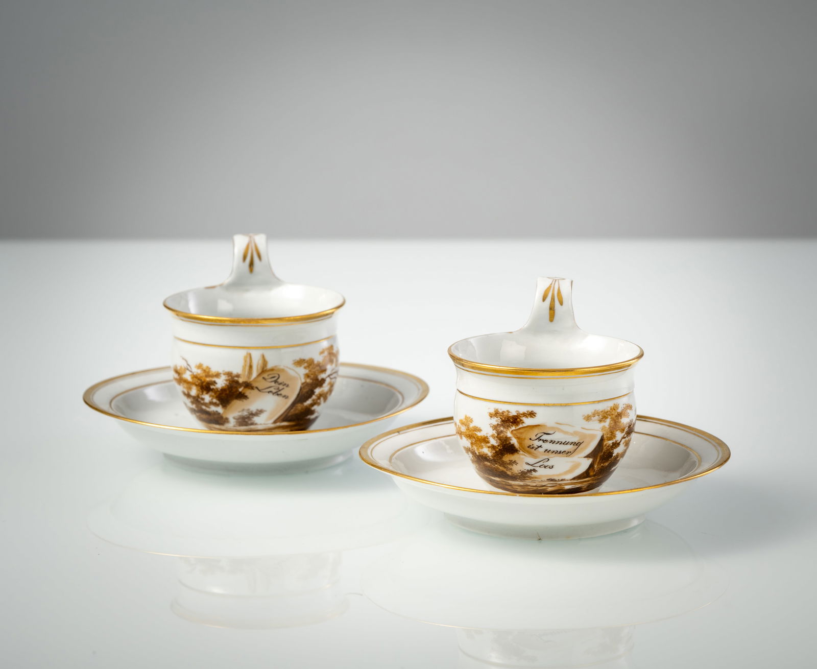 A PAIR OF MEMORIAL CUPS AND SAUCERS: A PAIR OF MEMORIAL CUPS AND SAUCERS German, circa 1790/1800 H. 7,5/D. 13,5 cm Painting on gravestones in shades of brown, in black lettering: ‘Your life is mine’ ‘and separation is