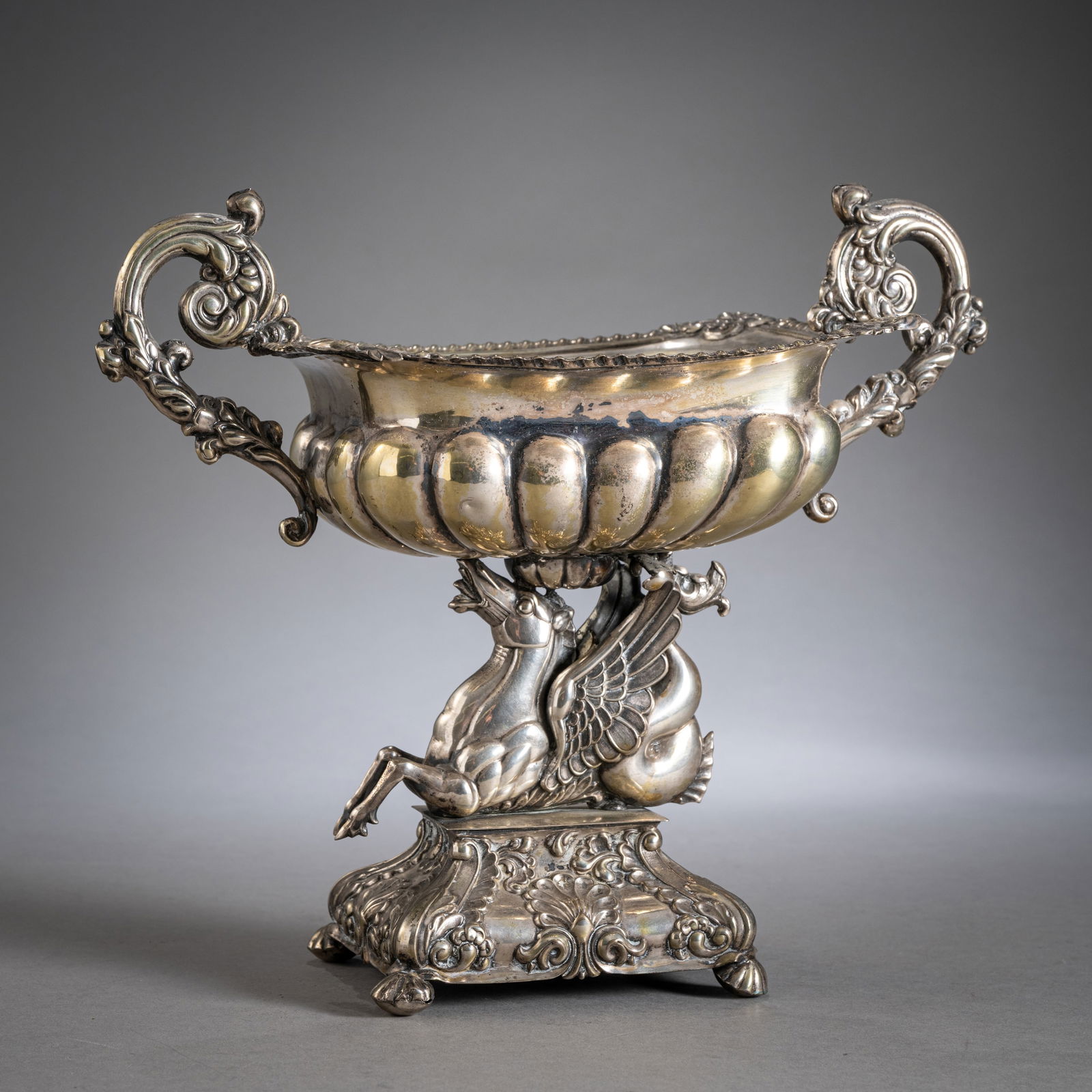 A BIEDERMEIER FOOTED DISH: A BIEDERMEIER FOOTED DISH mid 19th century H. 26 cm Plated metal. With Pegasus shaft and rocaille decoration. Slight age damages. The foot filled.Biedermeier-Aufsatzschale Mitte 19. Jhdt. H. 26 cm