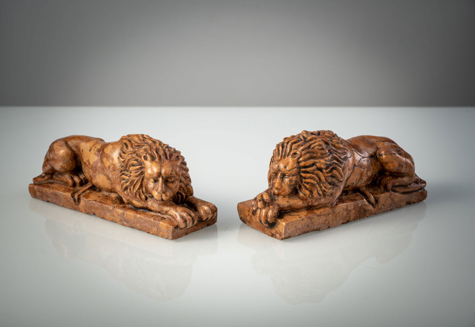 A PAIR OF ROSSO DI VERONA MARBLE LIONS: A PAIR OF ROSSO DI VERONA MARBLE LIONS Italy, 19th century L. 24 cm Red marble, carved in full round, the recumbant lions on rectangular plinth, chipped, minor cracks.Paar liegende Löwen