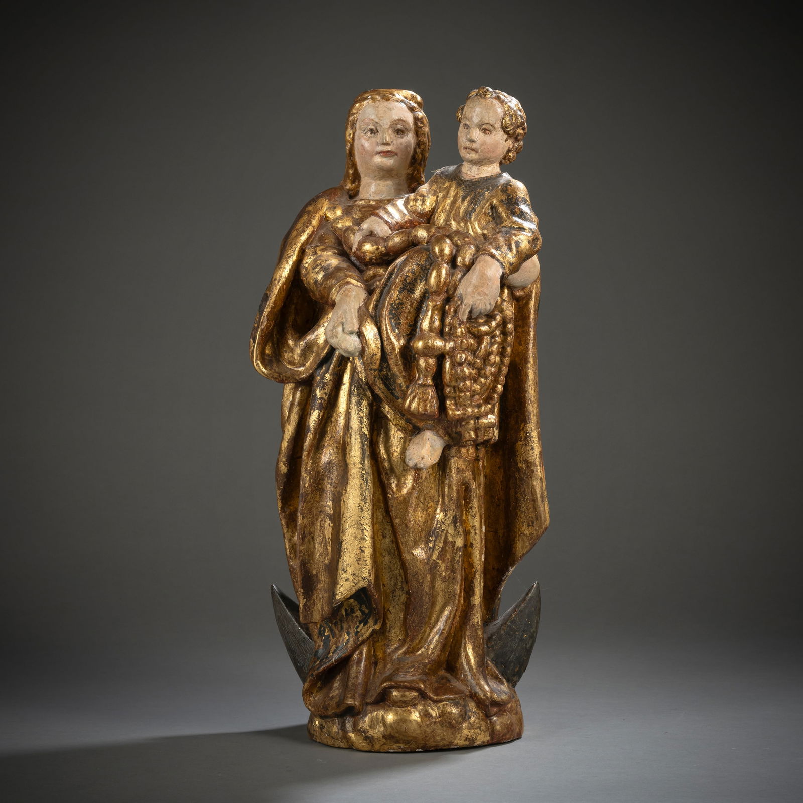 Madonna with child on the crescent moon with cord necklace and rosaries: Madonna with child on the crescent moon with cord necklace and rosaries Southern Europe, 17th/18th century H. 47 cm Hardwood, carved in full round. Polychromy, silvering and gilding with remnants of