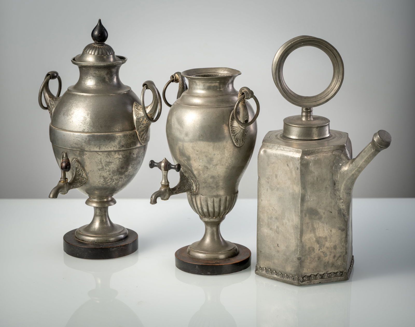 TWO PEWTER SAMOVARS AND A PEWTER SCREW BOTTLE: TWO PEWTER SAMOVARS AND A PEWTER SCREW BOTTLE 19th century H. 33-41 cm The bottle marked, one lid missing, dents, restorations.Zwei Dröppelminnas und Schraubkanne aus Zinn 19. Jhdt. H. 33-41 cm