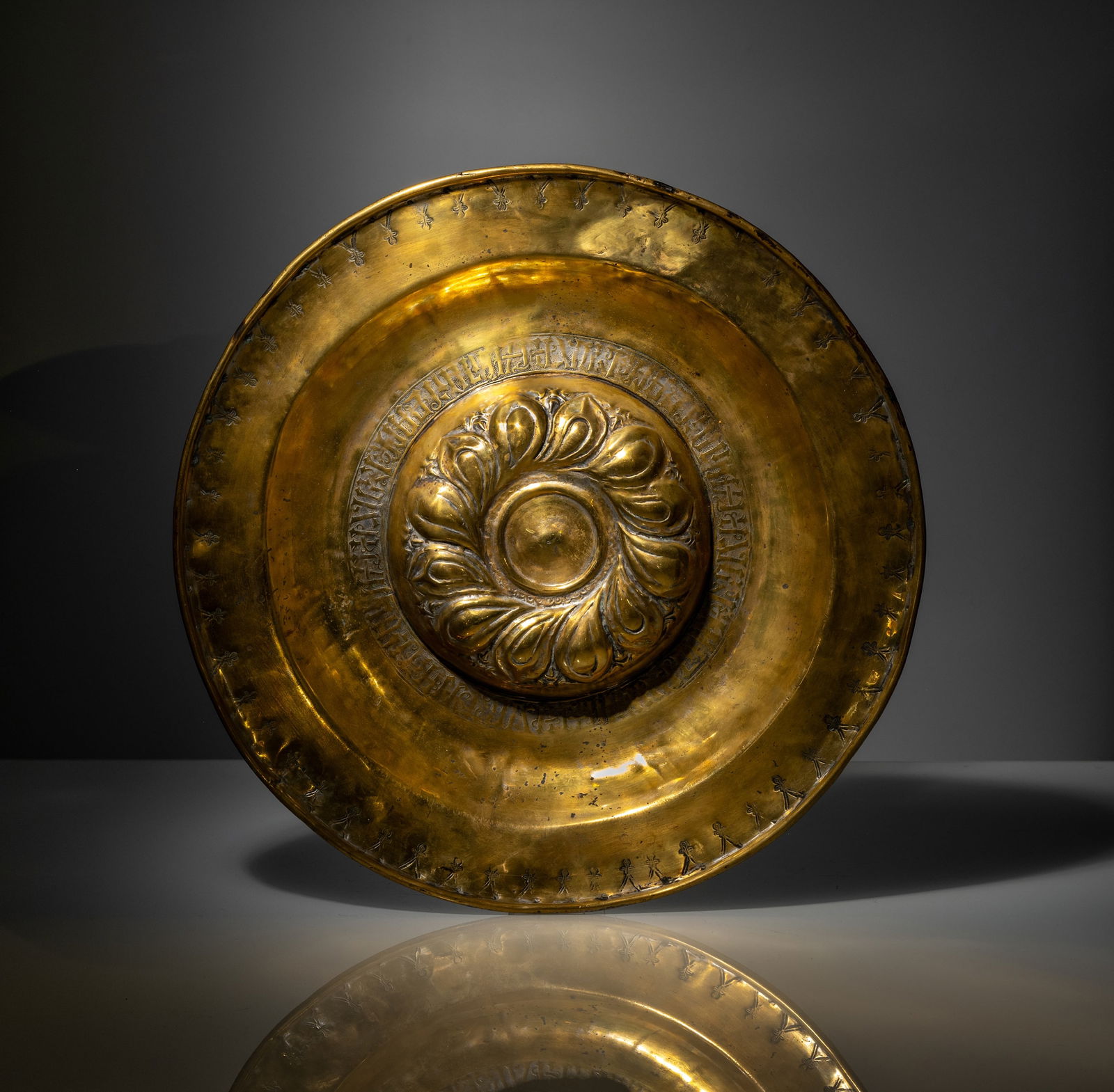 A LARGE SOUTH GERMAN EMBOSSED BRASS DISH: A LARGE SOUTH GERMAN EMBOSSED BRASS DISH probably Nuremberg, 16th/17th cent. D. 44 cm Brass, embossed and engraved, with fish bubble pattern and inscription. Signs of age, minor