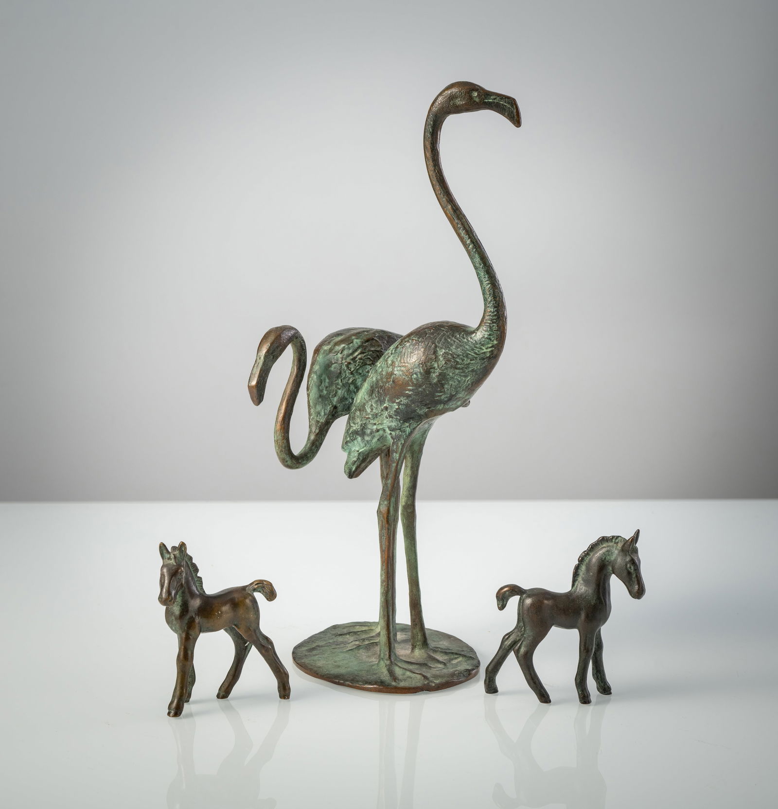 A PAIR OF FLAMINGOS AND TWO FOALS: A PAIR OF FLAMINGOS AND TWO FOALS 20th century H. 10/36,5 cm Bronze, patinated, not signed. Some verdigris.Flamingo-Paar und zwei Fohlenfiguren 20. Jhdt. H. 10/36,5 cm Bronze, patiniert. Anonym, ohne