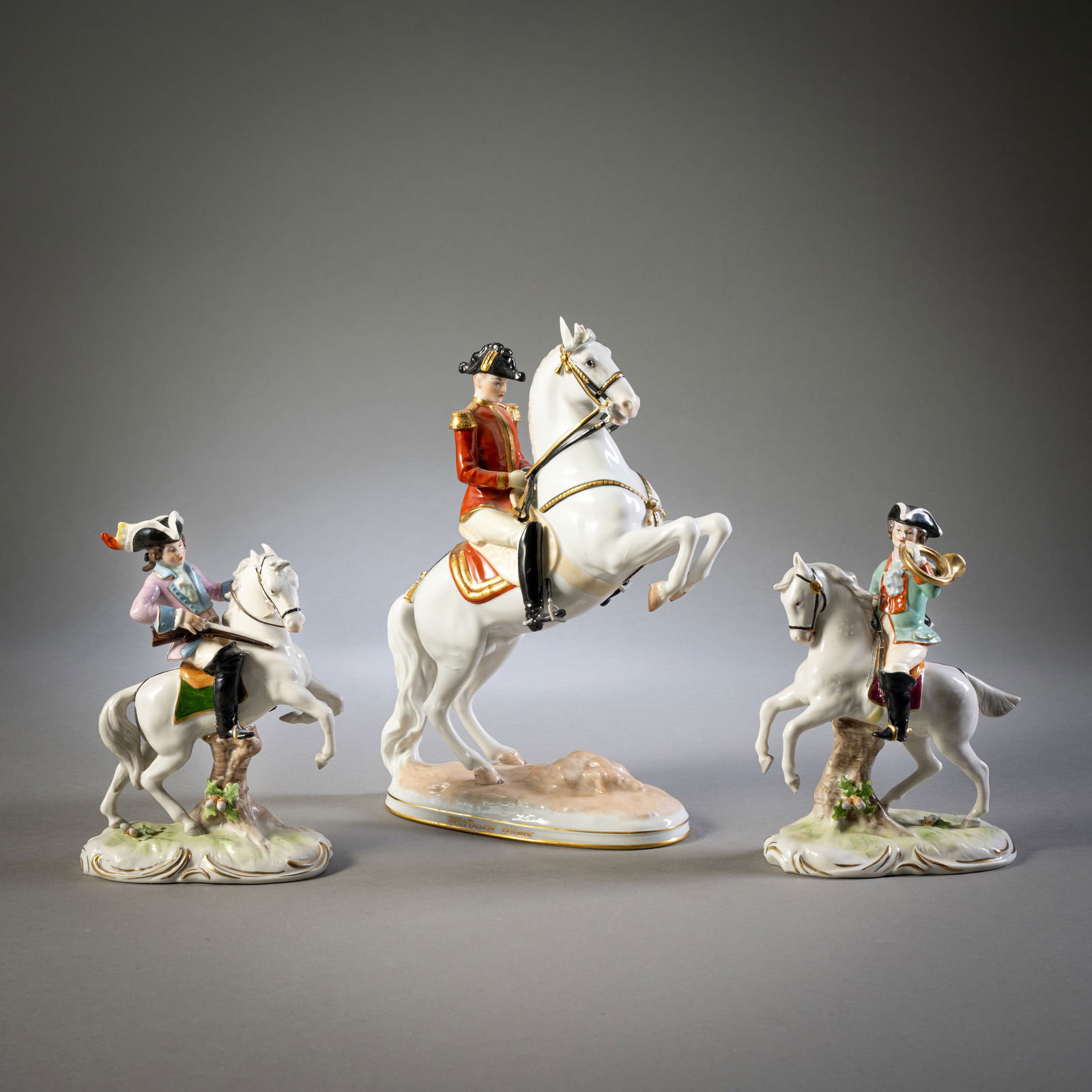 TWO HUNTSMEN AND SOLDIER: TWO HUNTSMEN AND SOLDIER Sitzendorf/ Vienna, 20th cent. H. 19/30 cm Two hunting riders, "Made in GDR" and soldier "Spanische Reitschule", polychrome painted and partly gilded, design after Dobrich,