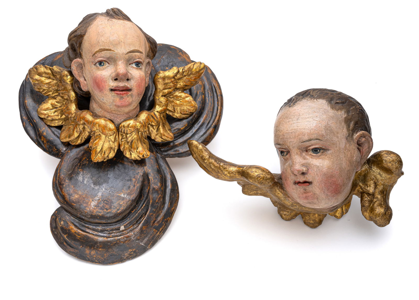 TWO WINGED PUTTO HEADS: TWO WINGED PUTTO HEADS South German, 18th century B. 26/H. 28 cm Broadleaf wood, carved in full-round, polychrome painted and gilt. A cherub mounted on a band of clouds made of softwood. The