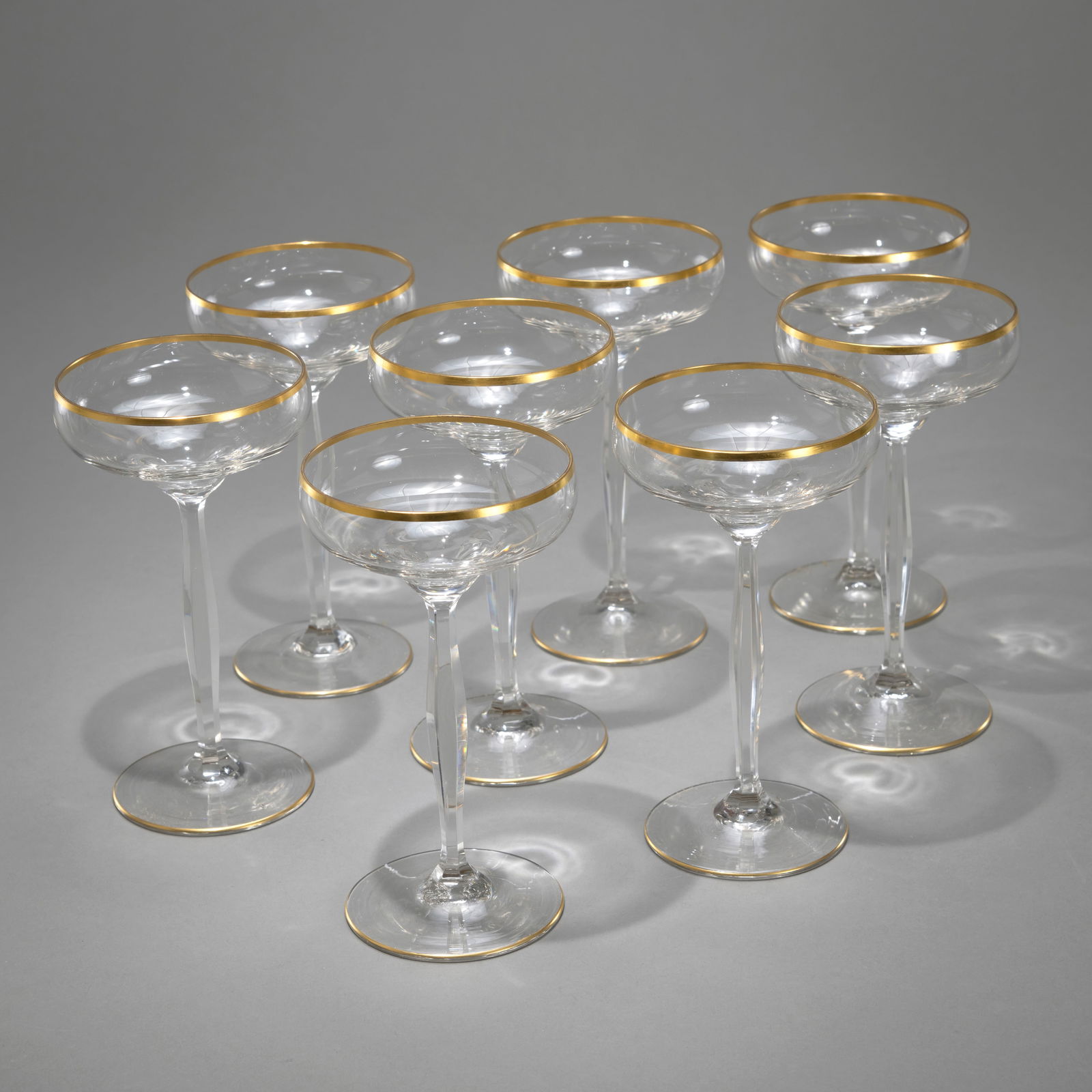 EIGHT ART NOUVEAU CHAMPAGNE GLASSES: EIGHT ART NOUVEAU CHAMPAGNE GLASSES Theresienthal, ca. 1900 H. 16,7 cm Colourless glass with gilt rim and stand. Minor wear and min. chipAcht Jugendstil Sektschalen mit Goldrand Theresienthal, um