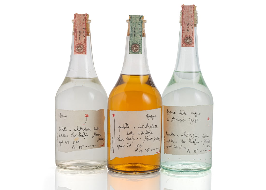 Levi, Romano: Levi, Romano Campodolcino.1928 - Neive, 2008 H. 26/27,5 cm 3 grappa bottles with labels designed by the artist and distiller. Ink on paper. All signed and dated “96” in ink at lower left.