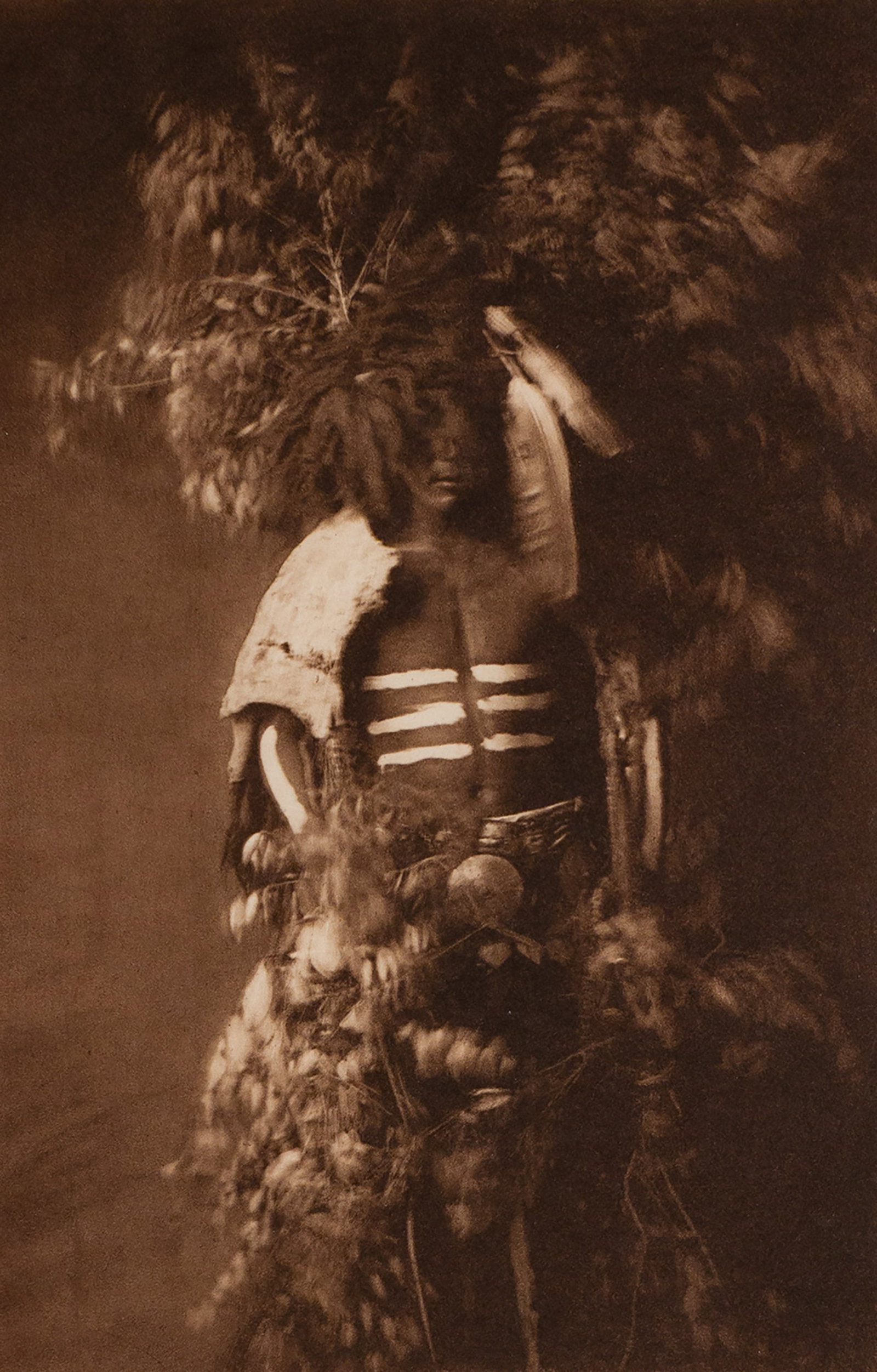Ready for Okipe Buffalo Dance - Mandan: This richly detailed image captures a Mandan man in full ceremonial regalia, prepared to perform the Okipe Buffalo Dance—a sacred component of the O-kee-pa ceremony. His chest is painted with bold w