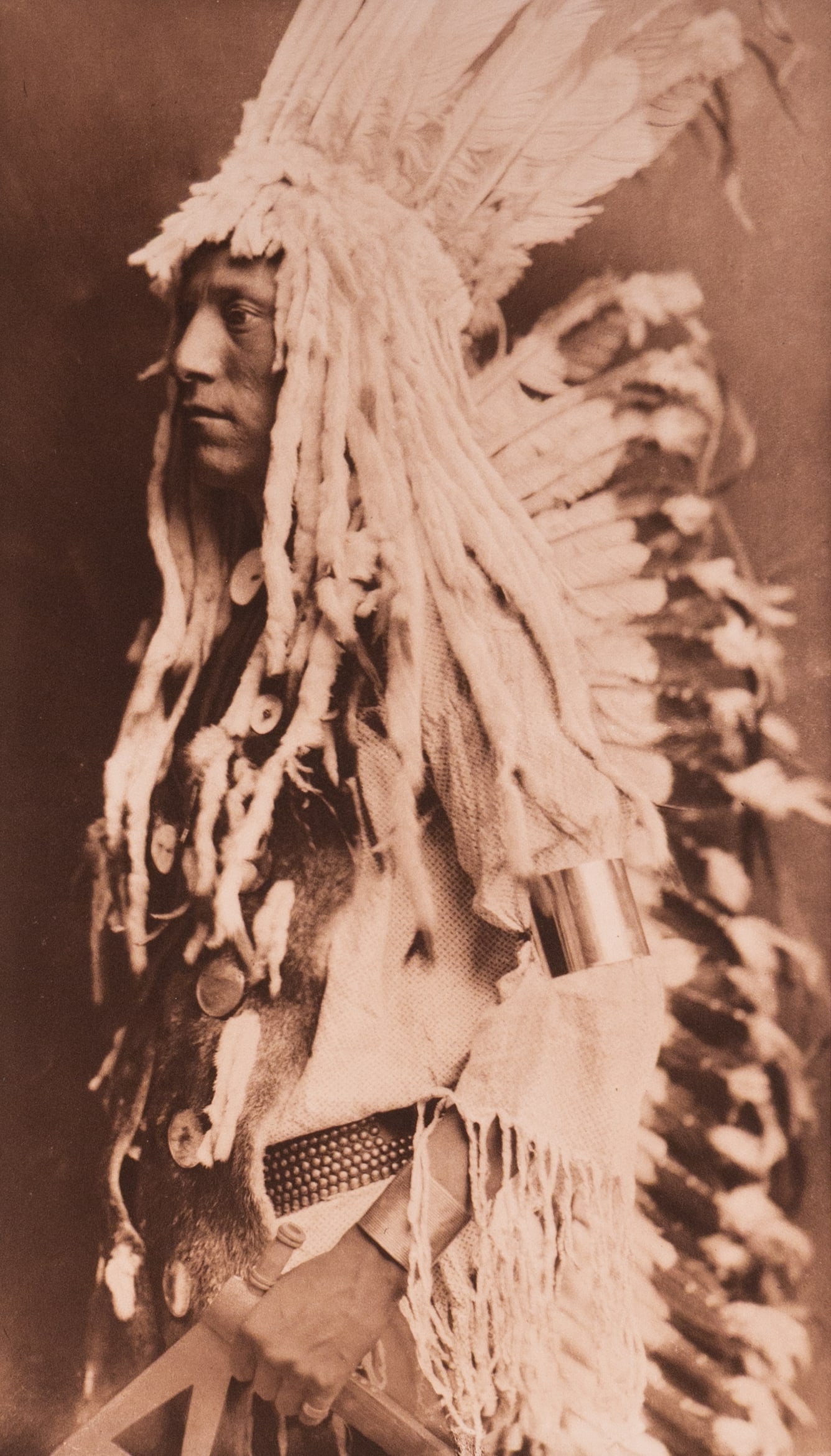 Old Person - Piegan: This photogravure is printed on Holland van Gelder paper. A deeply expressive portrait of a Piegan elder wrapped in a robe, shown in three-quarter profile. His weathered face, lined with age and exper