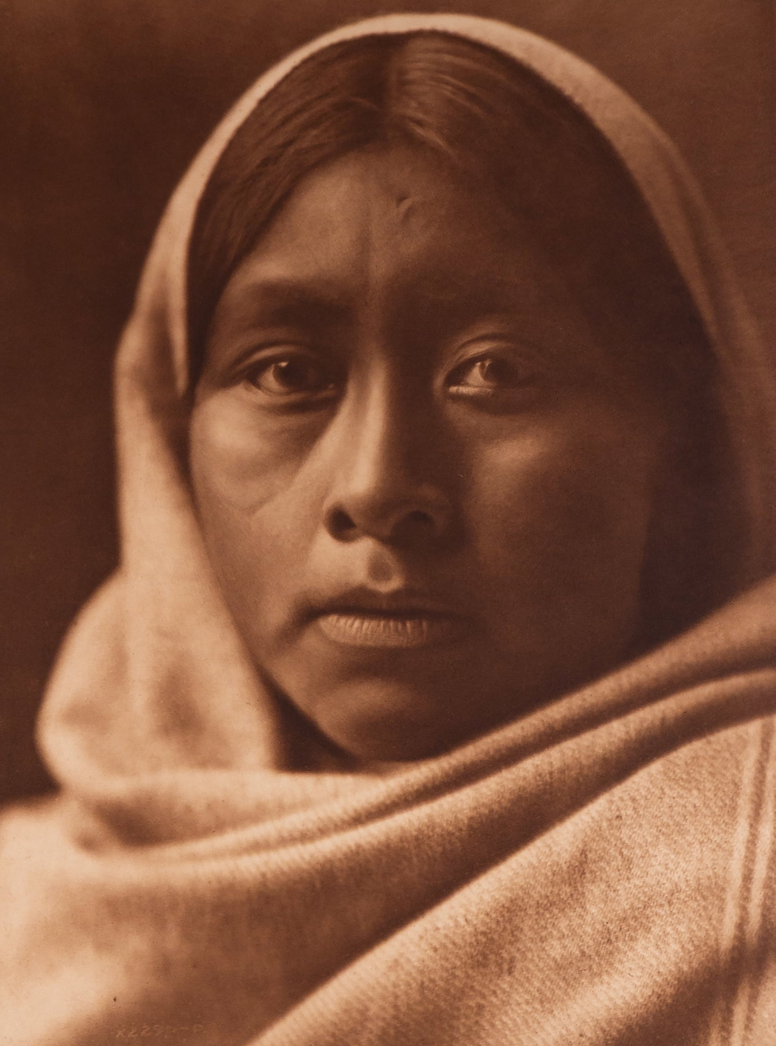 Papago Girl: This Curtis photogravure is on Japanese Gampi Tissue paper. A luminous and intimate portrait of a young Papago (Tohono O'odham) girl, draped in a head shawl and gazing directly into the lens. Her expr