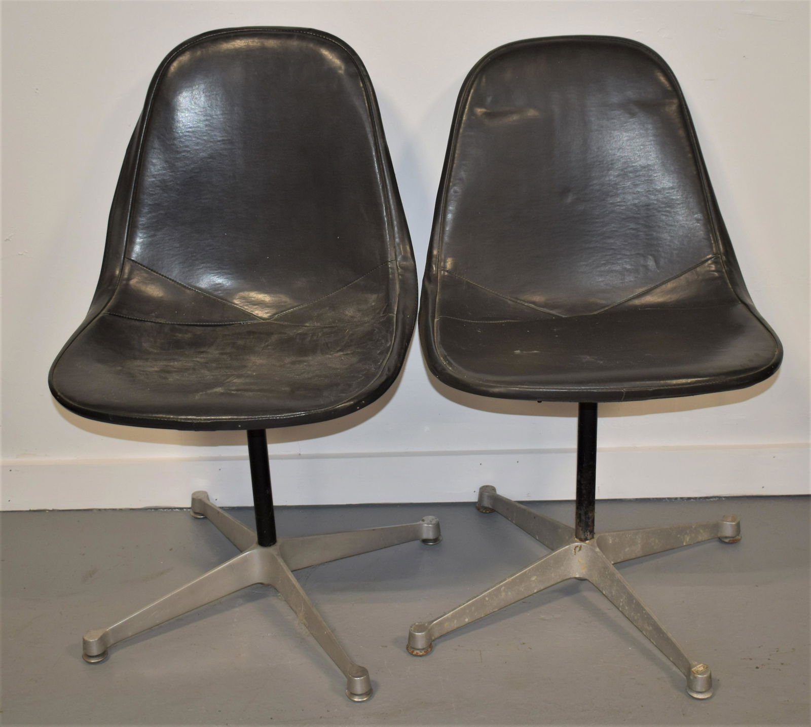 Pair of Charles Eames Style Chairs: 2 BLACK LEATHER SWIVEL CHAIRS WITH BLACK WIRE SQUARE GRID BACK WITH CHROME BASE- ATTRIBUTED TO CHARLES EAMES- 32 1/2" T - SEATS 18" H- WEAR, DAMAGES AND IMPERFECTIONS
