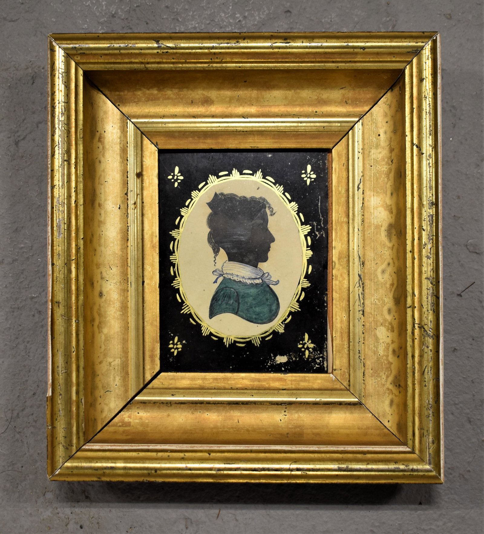 19th Century Watercolor Cut Paper Silhouette: 19TH CENTURY WATERCOLOR AND CUT PAPER SILHOUETTE OF YOUNG LADY WITH GREEN DRESS AND WHITE AND BLUE COLLAR- REVERSE PAINTED GLASS MATTING/ SORROUND IN A DEEP WIDE LEMON GOLD MOLDED WOODEN FRAME- 5" X 3
