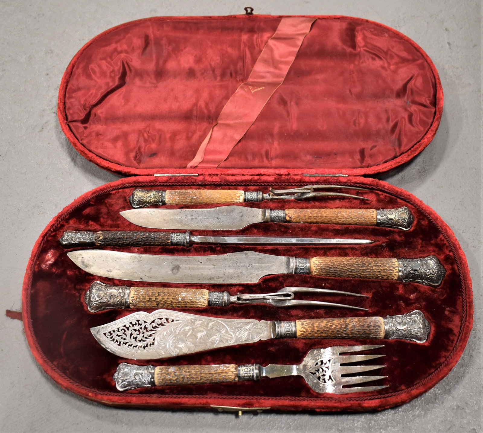 Fancy Victorian Silverplated Carving Set: LATE 19TH CENTURY ENGLISH 7 PIECE SILVERPLATED CARVING SET WITH HORN HANDLES - ALL IN FITTED RED VELVET CASE - FLORAL ETCHED BLADES AND FANCY REPOUSSE END CAPS - C.D. PEACOCK CHICAGO ON CASE - FLATWAR