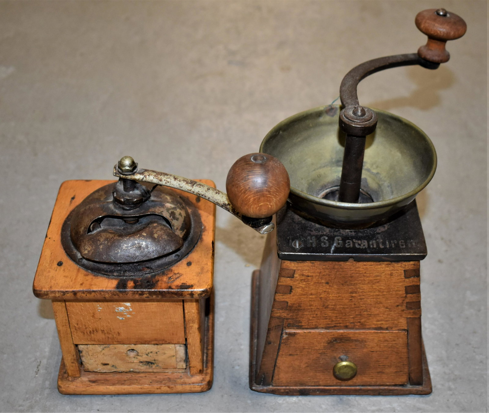 (2) Continental Wooden Coffee Mills: (1) SMALL EARLY 20TH CENTURY WOODEN COFFEE MILL WITH TIN HOPPER AND LOWER DRAWER - 4 1/4" SQ X 7 3/4"T - (1) GERMAN WOODEN AND IRON COFFEE MILL MARKED "H.S. GARANTIREN" - 4 1/2" X 4 1/2" CANTED X 8 1/