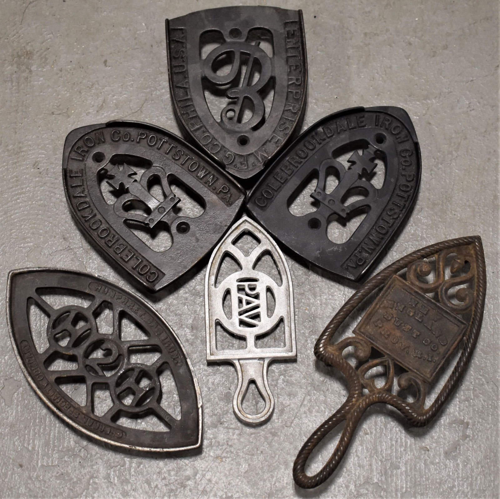 Lot (6) Cast Iron Advertising Trivets: (2) COLEBROOKEDALE ENTERPRISE, HUMPHREY GAS IRON/GEN SPECIALTY CO., N.E. BUTT CO., PA - IMPERFECTIONS