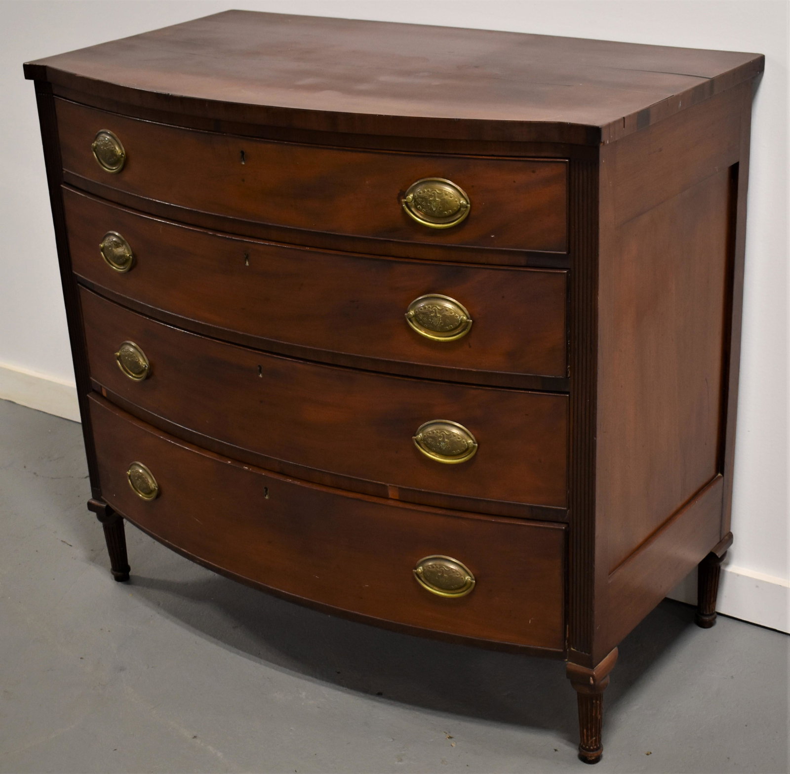 N. E. Hepplewhite Bowfront 4 Draw Chest: N.E. HEPPLEWHITE MAHOGANY 4 DRAW CHEST - BOWFRONT WITH REEDED FRONT 1/4 COLUMNS - ON TURNED AND REEDED FEET - OVAL BRASSES WITH EAGLE AND SHIELD - 38"T X 40 1/2"W X 23 1/2" - SPLIT ON TOP - SMALL VENE