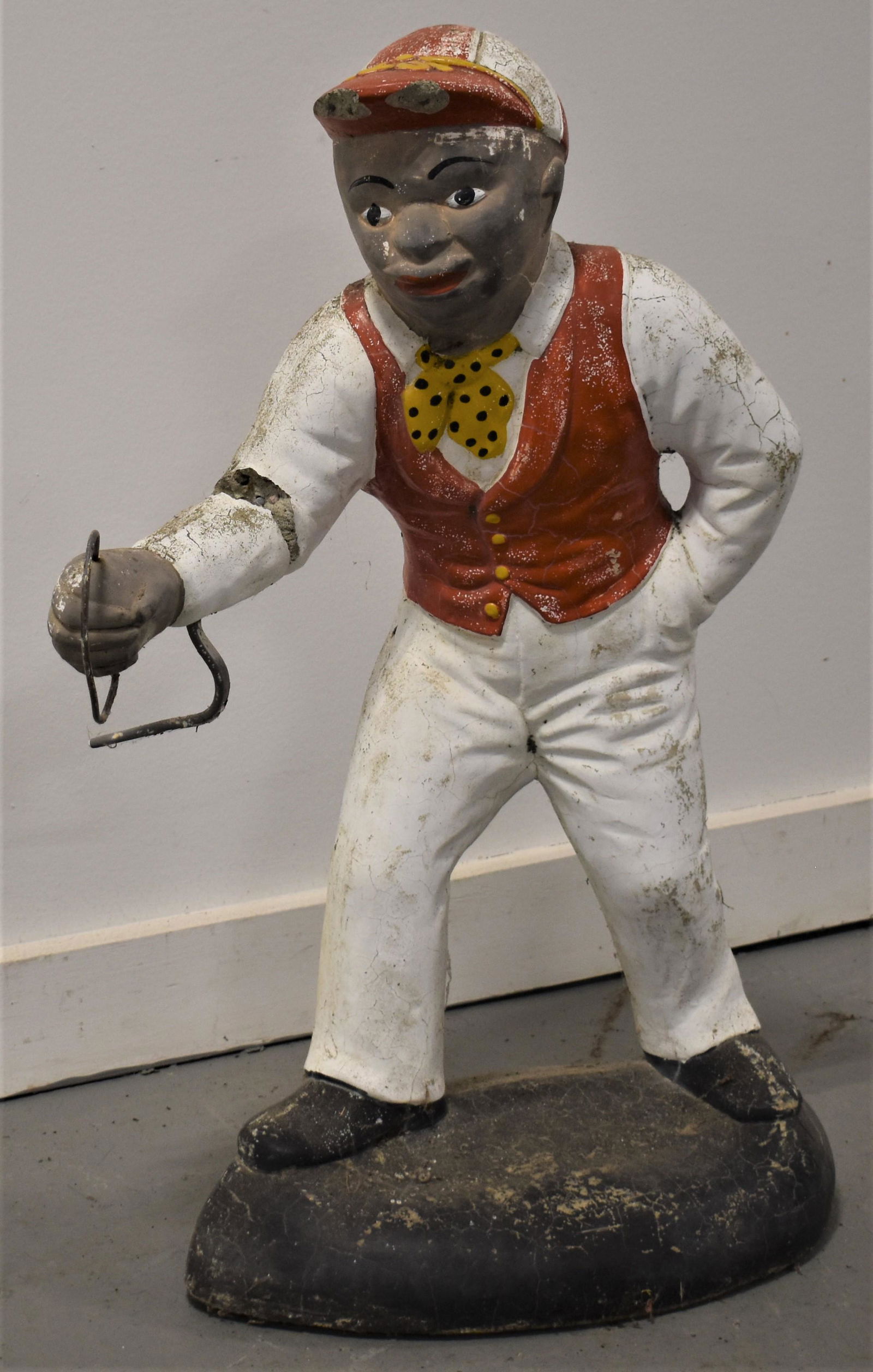 Painted Concrete Lawn Jockey: 20TH CENTURY PAINTED CAST CONCRETE LAWN JOCKEY- 25"T - CHIPS TO BRIM OF HAT, CRACKED ARM, WIRE SNIPED, WEAR AND LOSSES TO PAINT, IMPERFECTIONS