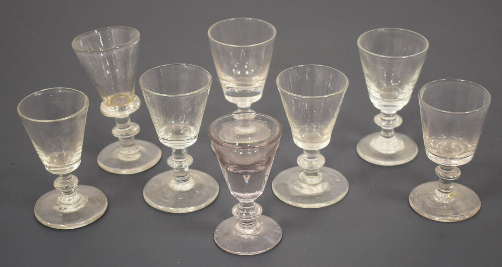(7) Early Flint Glass Cordials: LOT (7) EARLY FLINT GLASS CORDIALS W/ RING FORM STEMS- TOGETHER W/ (1) LATER CORDIAL 4 1/4"- 3 1/2"- WEAR AND IMPERFECTIONS