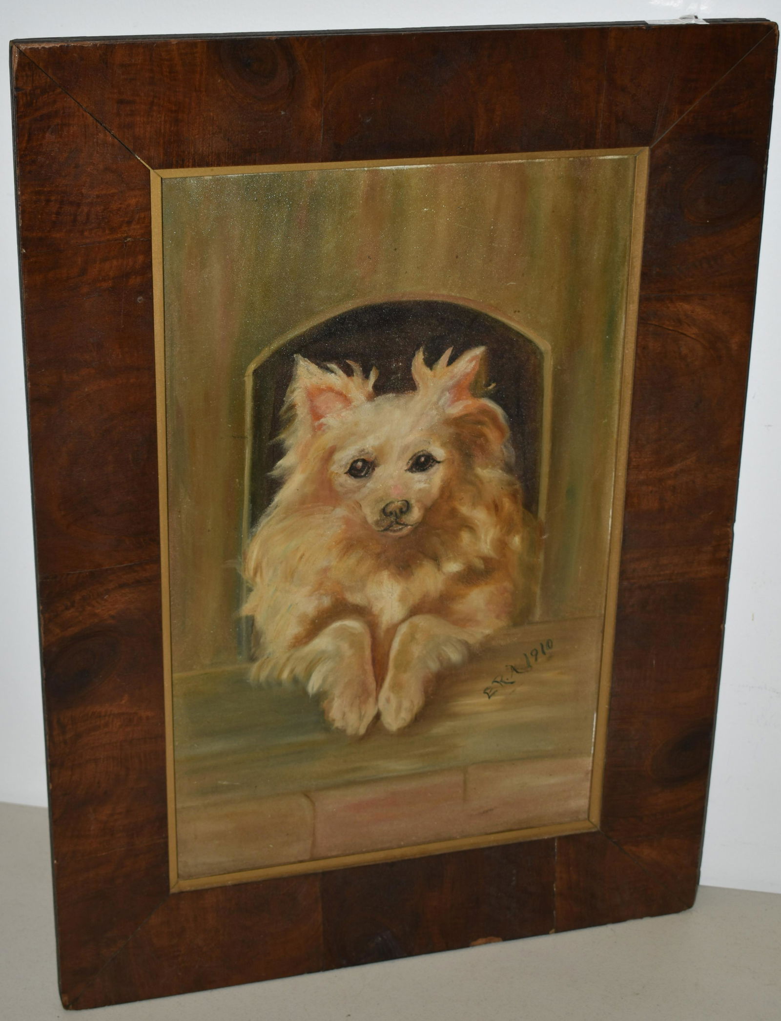 DOG OIL PAINTING ON ARTIST PANEL: EARLY 20TH CENT OIL PAINTING OF DOG LOOKING OUT & THRU DOG HOUSE OPENING - SIGNED ERA 1910 LOWER RIGHT - IN A MAHOGANY VENEER FRAME - 18" X 11" - WEAR, LOSSES TO VENEER FRAME & IMPERFECTIONS