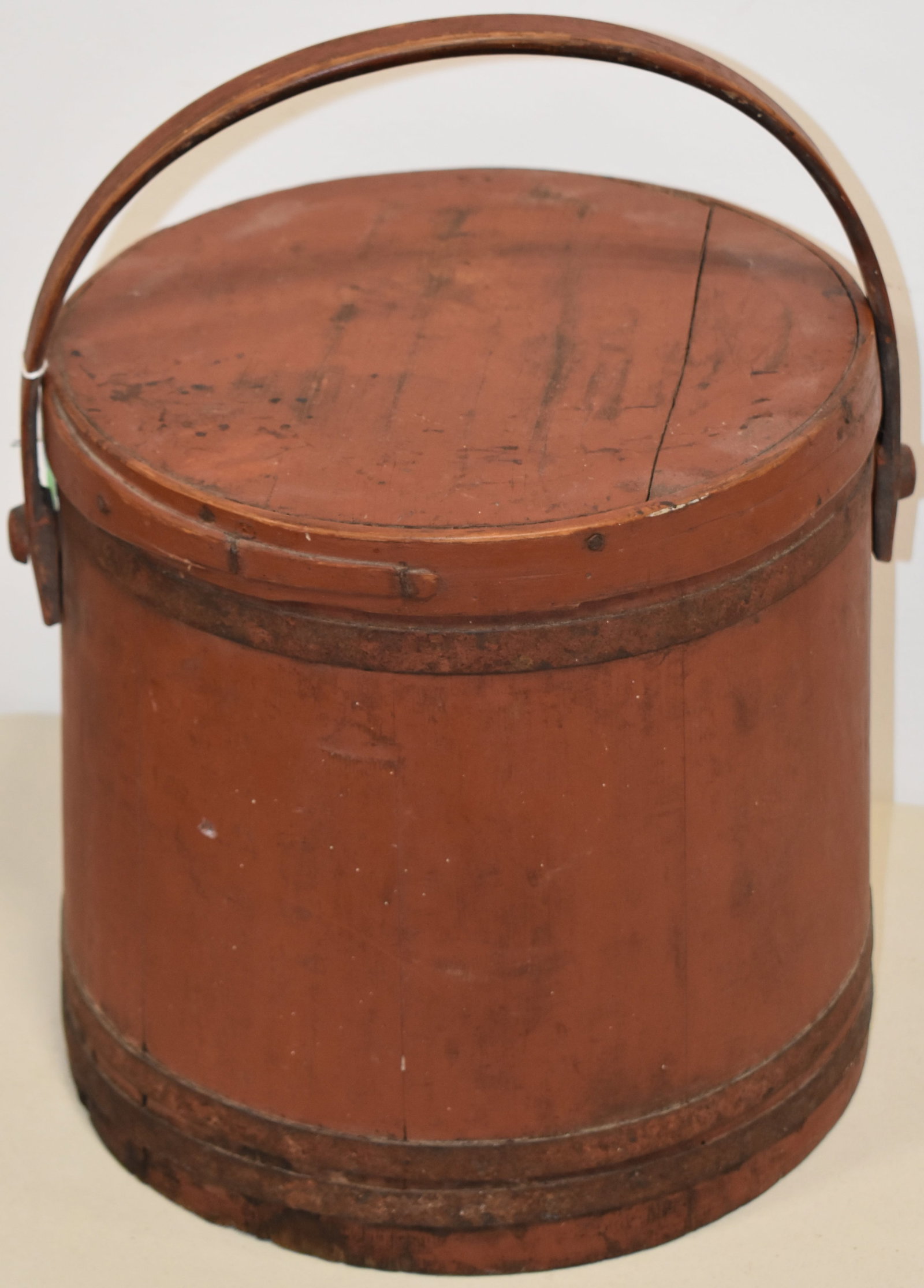 19TH CENT PAINTED WOODEN FIRKIN: 19TH CENT WOODEN FIRKIN IN OLD RED PAINT - BASE W/ IRON BANDS - TOP W/ FINGER BAND W/ FLAT WOODEN BAIL HANDLE - 17" T W/ HANDLE - BUCKET 12" T - TOP 12 1/4" DIA - BASE 13" DIA - SPLITS IN TOP - WEAR &