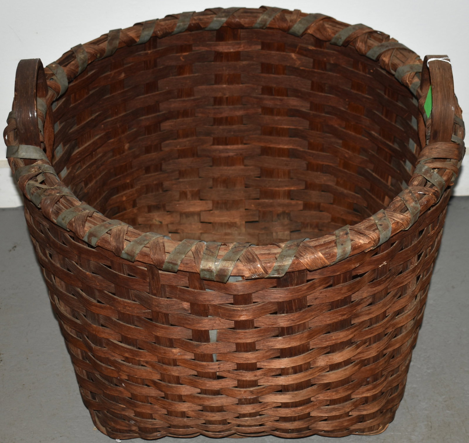LARGE SPLINT GATHERING BASKET: LATE 19TH EARLY 20TH CENT HANDLED SPLINT GATHERING BASKET W/ SPLINT & TIN WRAP AROUND TOP & THRU BOTTOM OF BASKET - STATIONARY BENT WOODEN HANDLES - 19" T X 22" DIA - WEAR & IMPERFECTIONS