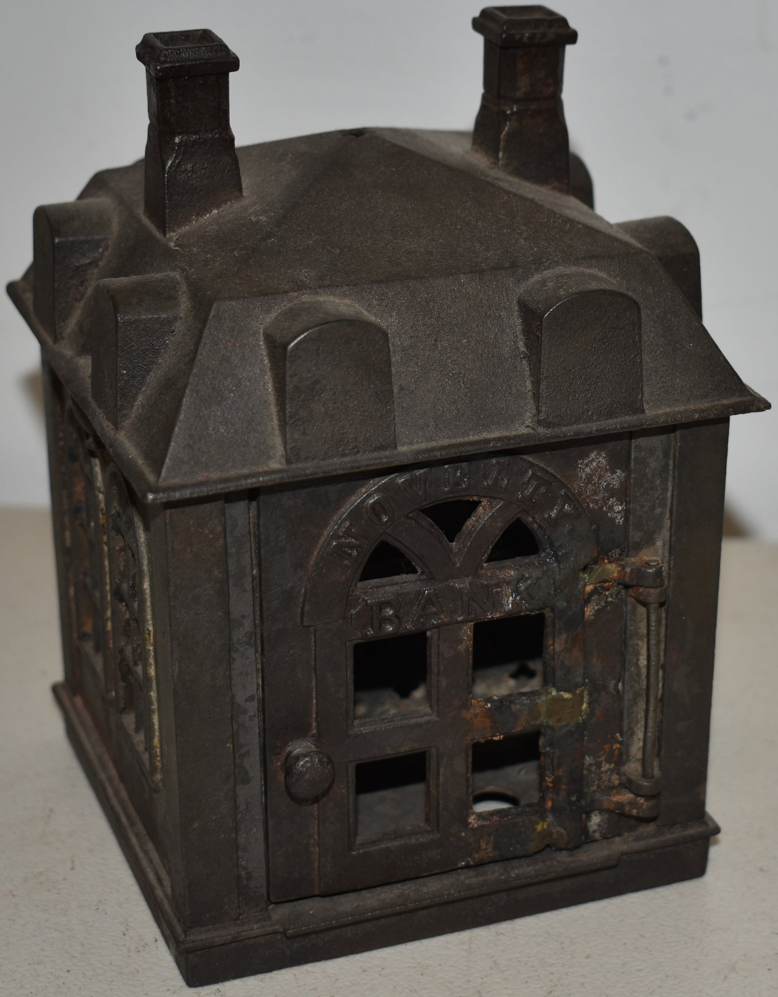 CAST IRON NOVELTY BUILDING COIN BANK: CAST IRON BANK BUILDING COIN BANK MARKED ON FRONT DOOR NOVELTY BANK - 6 3/4" T X 4 3/8" SQ. - UNPAINTED - OXIDATION, WEAR & IMPERFECTIONS