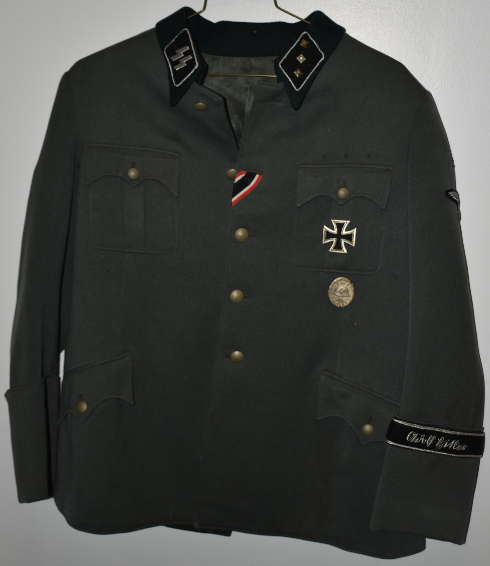 WWII GREEN GERMAN MILITARY DRESS WAIST COAT: GREEN WOOL DRESS COAT W/ SS LOGO PATCH & 3 STAR PATCH ON COLLAR - IRON CROSS & NAZI WOUND BADGE FRONT & 1941-42 METAL PATCH W/ EAGLE 1941-42 -KRIM ON SLEEVE & OTHER PATCHES - NAME BAND ON SLEEVE - IMP