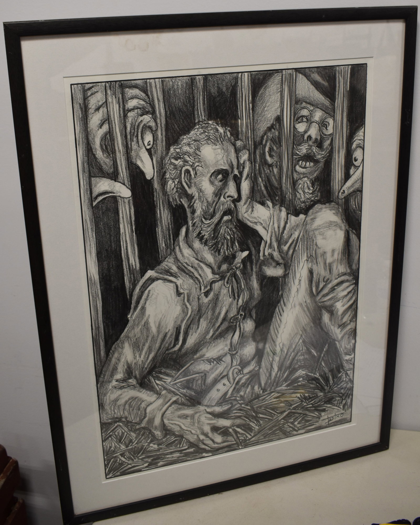 CHARCOAL DRAWING OF A MAN BEHIND BARS: 20TH CENT FRAMED CHARCOAL DRAWING OF A MAN SEATED ON GRASS OR STRAW BEHIND BARS WITH 3 MEN PEERING IN - SIGNED CASTRO OR FASTRO LOWER RIGHT - 26 1/2" X 18 3/4" SIGHT - MATTED & FRAMED - TONING