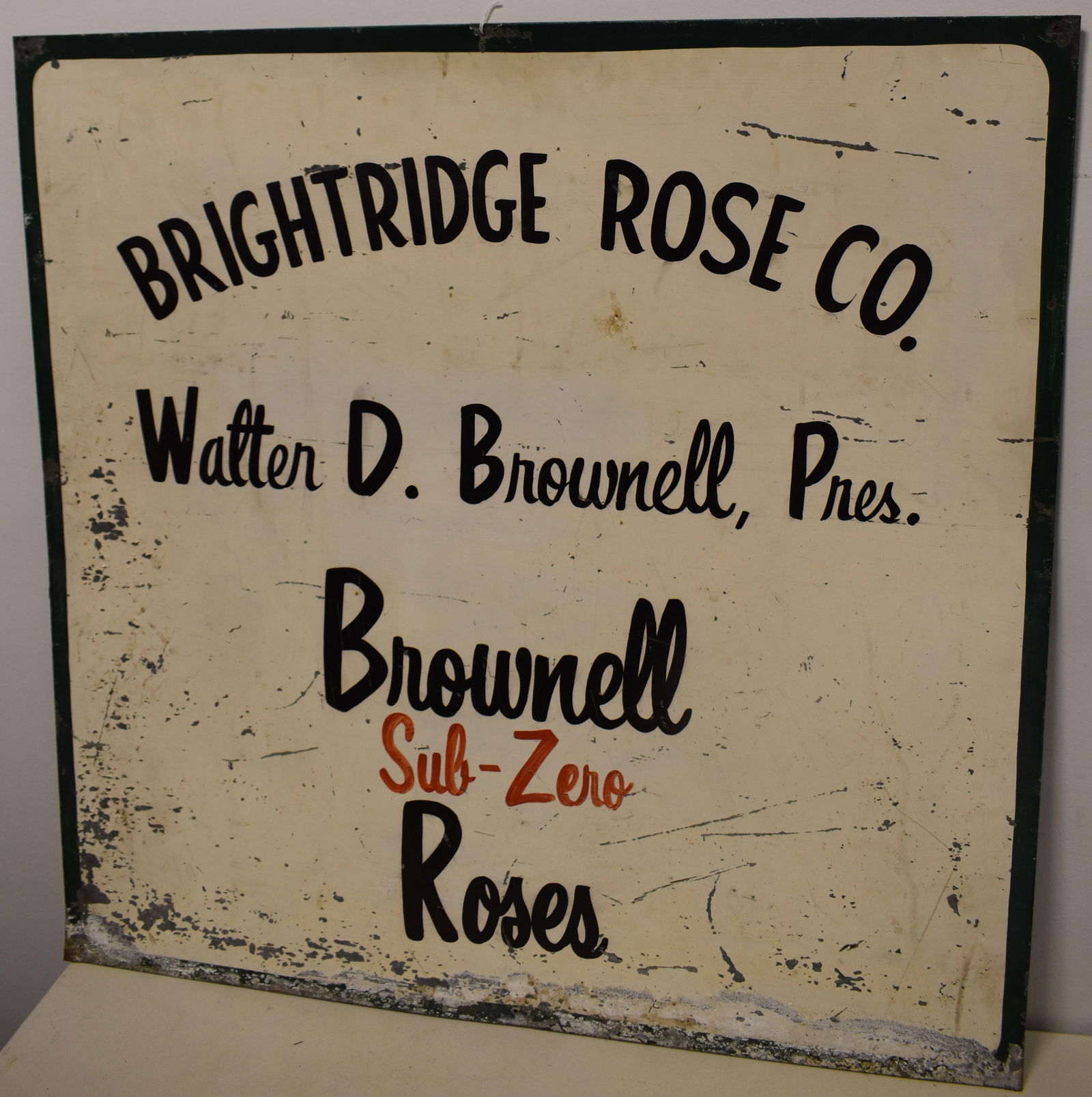 VINTAGE PAINTED TIN ADVERTISING SIGN: EARLY 20TH CENT PAINTED GALVANIZED TIN SIGN - BRIGHTRIDGE ROSE CO. - WALTER D. BROWNELL, PRES - BROWNELL SUB - ZERO ROSSES - 35" X 35 1/4" - SINGLE SIDED - WEAR, LOSSES TO PAINT, FLAKING, OXIDATION &