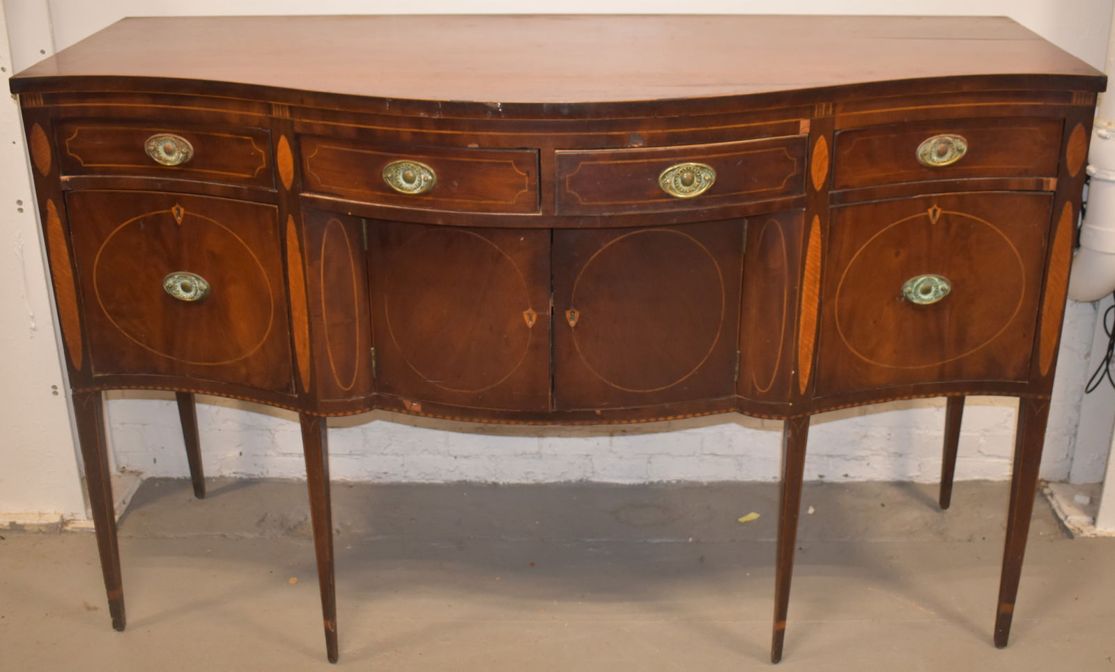 AMERICAN INLAID MAHOGANY SIDEBOARD: MAHOGANY HEPPLEWHITE INLAID SERPINTINE FRONT SIDEBAORD W/ CHECKERED & LINE INLAY W/ TIGER MAPLE OVAL INLAID PANELS - OLD OVAL BRASSES ON SQAURE TAPERED LEGS W/ INLAID CUFFS - 43" T X 68 3/4" W X 28 3/