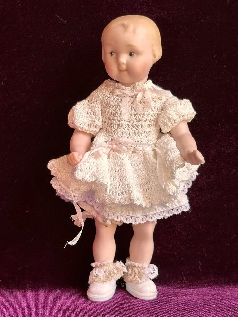 All Porcelain 7" Reproduction of Antique German Armand Marseille Girl 210 Doll: Very sweet miniature all-porcelain doll. She is in overall very good condition, with no damage to the porcelain. There are some small handwork imperfections, including one to the right arm that appear
