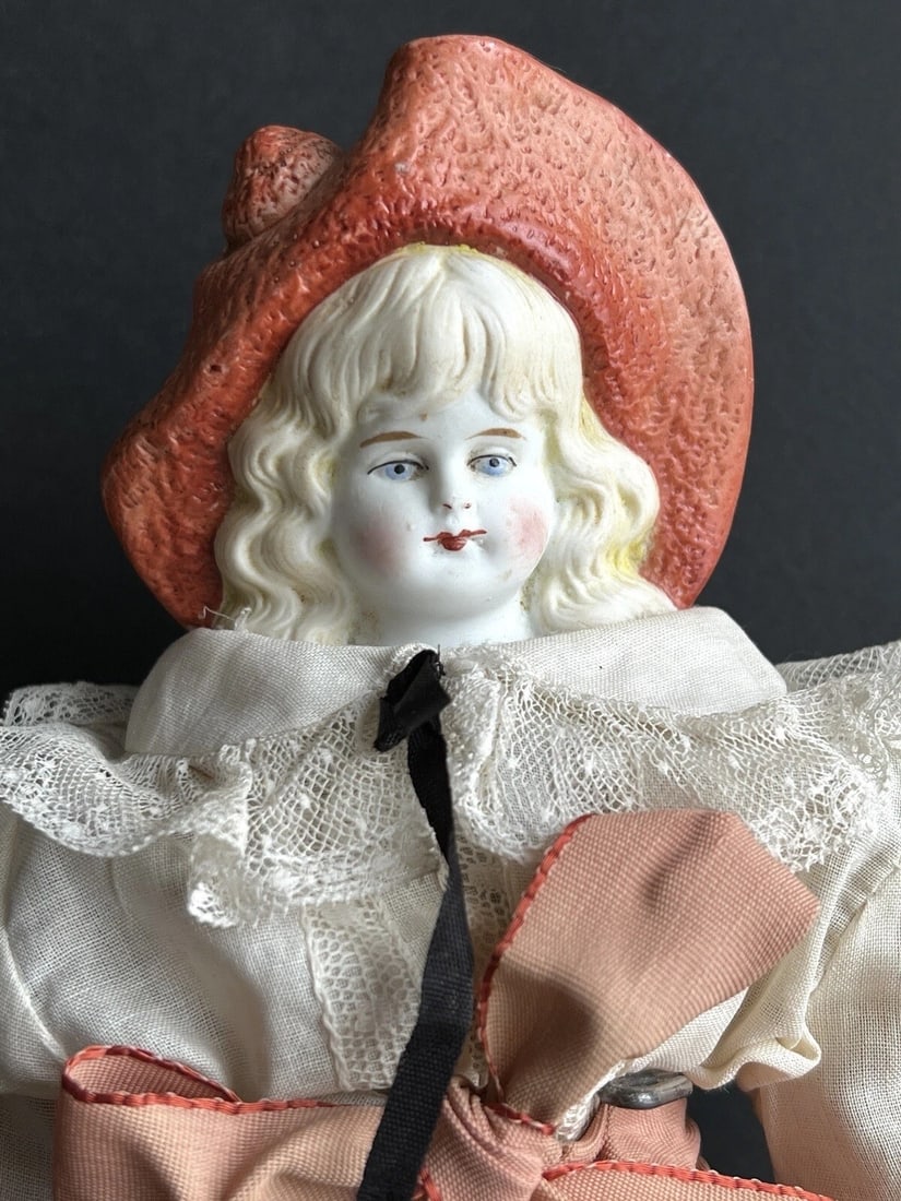 Antique German Hertwig 11.5" Molded Hat Bisque Shoulder Head Doll: Hard to find old doll. The head has small mold and paint imperfections. Possibly some paint touch ups to the face. A couple small chips to the shoulder plate. The body is an old replacement. Some stai