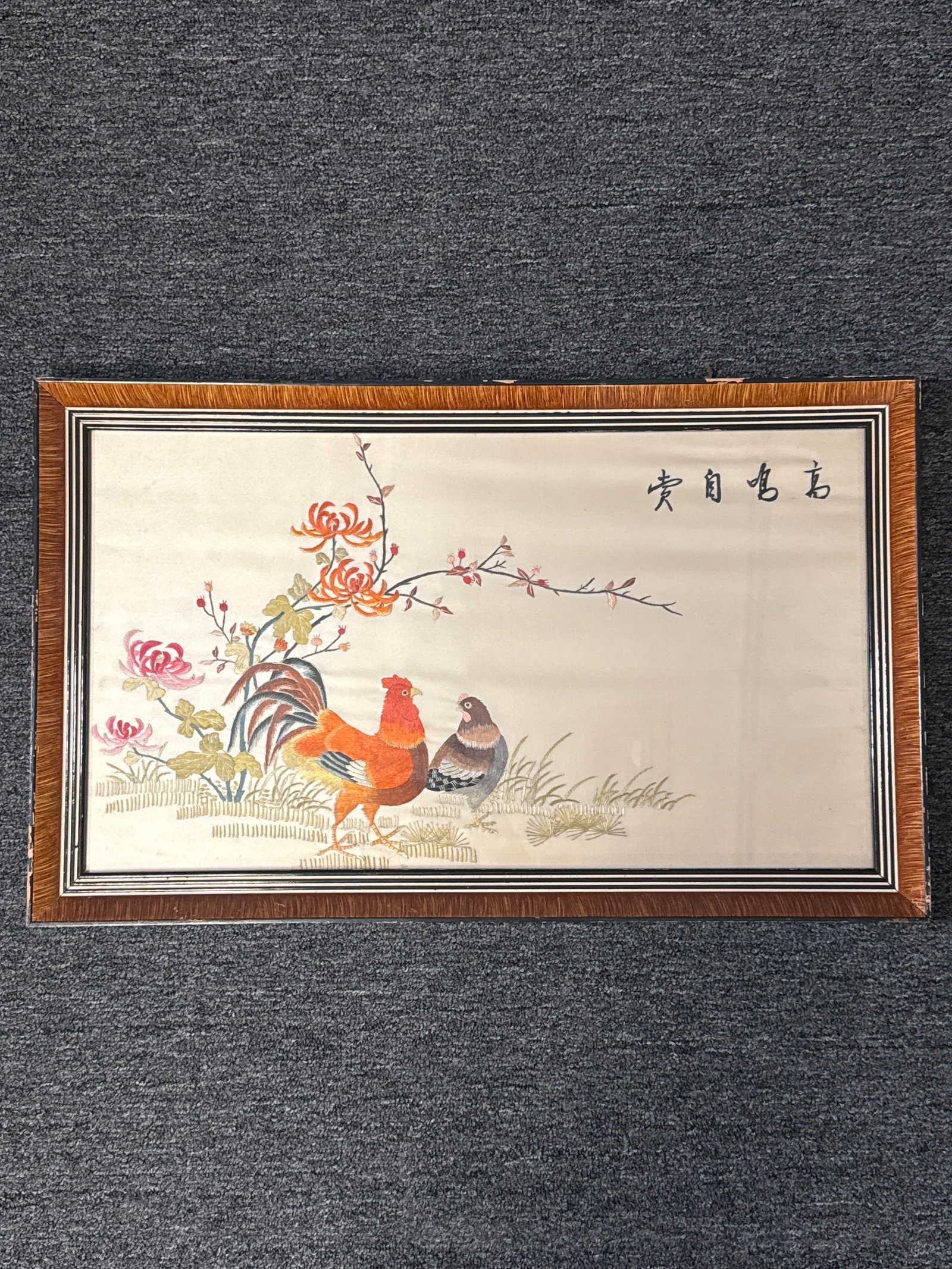 Vintage Chinese Silk Embroidery of Rooster Pair with Blossoms: 24.5” x 15” Framed Textile ArtThis captivating vintage Chinese silk embroidery depicts a proud rooster and his companion hen standing gracefully beneath blooming chrysanthemums and delicat
