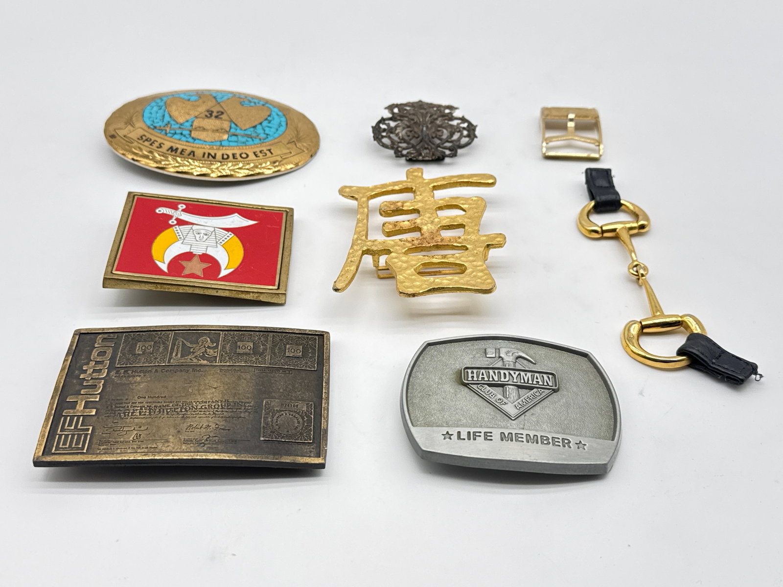 Belt Buckles, Emblems & Printing Die – Including E.F. Hutton, Shriners & Scottish Rite (138 white): A fascinating and eclectic mix of vintage and collectible Freemason and fraternal memorabilia. This lot includes:(1) Large heavy-duty steel die with engraved 14th Degree Scottish Rite collar jewel (ap