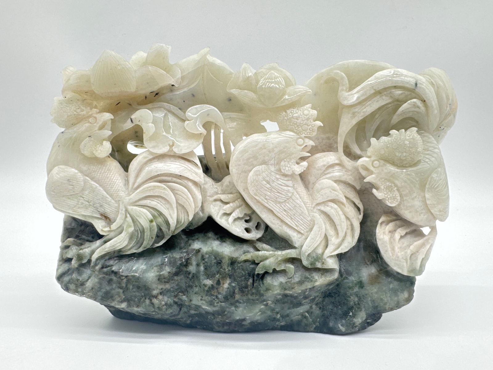 Intricately Carved Rooster Scene Sculpture on Natural Base (150 white): This striking decorative sculpture features an elaborate high-relief tableau of roosters and blooming flora, all perched atop a contrasting stone base. While the exact material is unconfirmed, the upp