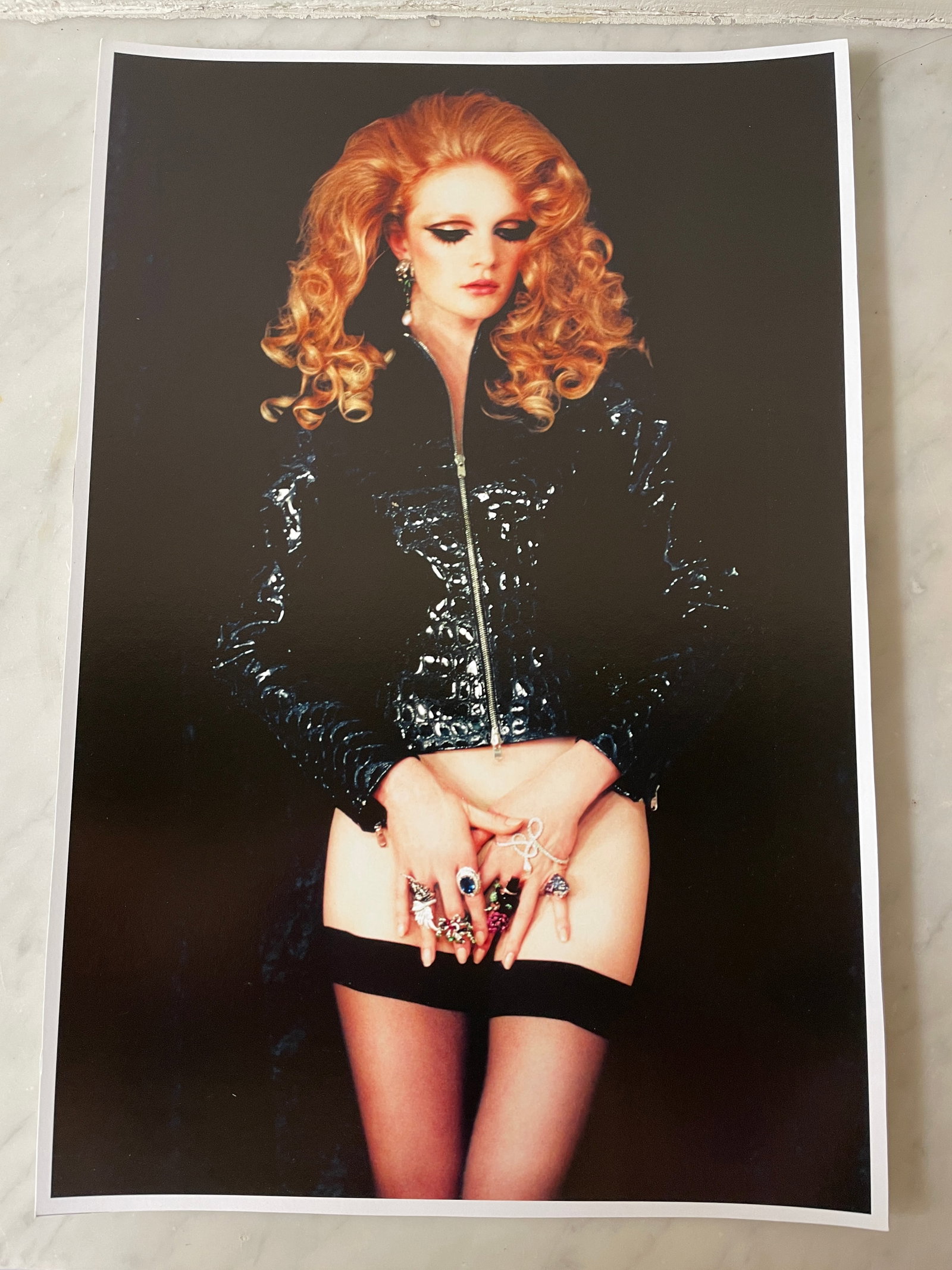 Irina Ionesco (1930–2022) – Woman in a Black Patent Jacket and Hold-ups – Original Photograph: Irina Ionesco (1930–2022) – Woman in a Black Patent Jacket and Hold-ups – Original Photograph Color photograph of a red-haired woman with voluminous curls, heavy makeup, and a theatrical appeara