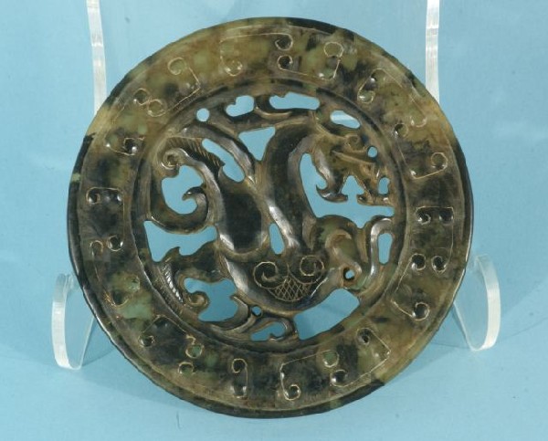NEPHRITE JADE DOUBLE DRAGON BI DISC: WELL CARVED NEPHRITE JADE BI DISC, HAVING A HAN DYNASTY STYLE PIERCED CENTRAL DRAGON DOUBLE-SIDED DESIGN, WITHIN A DOUBLE BAND OF INTERLOCKING C-SCROLLS, WITH EXCELLENT MULTI-COLOR STONE WITH FINE TRA