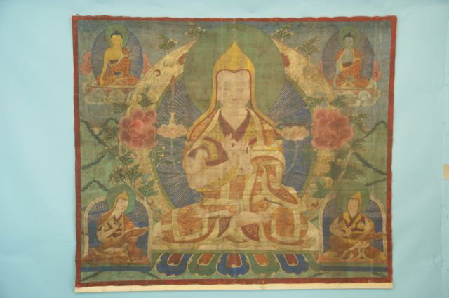 ANTIQUE TIBETAN TANGKA, CIRCA 1900-1910: ANTIQUE TIBETAN TANGKA, THE SCALE OF WHICH WAS INTENDED TO HANG IN A LARGE TEMPLE. THE CENTRAL FIGURE IS THAT OF PADMA SAMBHAVA, THE FOUNDER OF THE GELUKPA SECT OF TIBETAN BUDDHISM. HE IS SEATED ON A