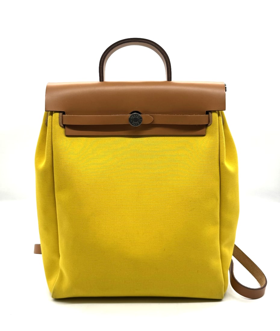 Hermes Military Toile Vache Hunter Herbag a Dos Zip Retourne Backpack Yellow: Hermes Military Toile Vache Hunter Herbag a Dos Zip Retourne Backpack YellowThe Hermes Military Toile Vache Hunter Herbag a Dos Zip Retourne Backpack in Yellow is a stylish and luxurious unisex backpa