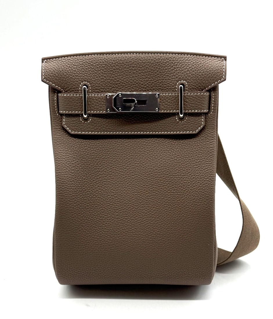 Hermes Hac a Dos PM Backpack 18 Etoupe Togo Leather: The Hermes Hac a Dos PM Backpack 18 in Etoupe Togo leather is a medium-sized women's backpack crafted from luxury leather with a solid pattern in a rich etoupe color. The bag features brown leather ha