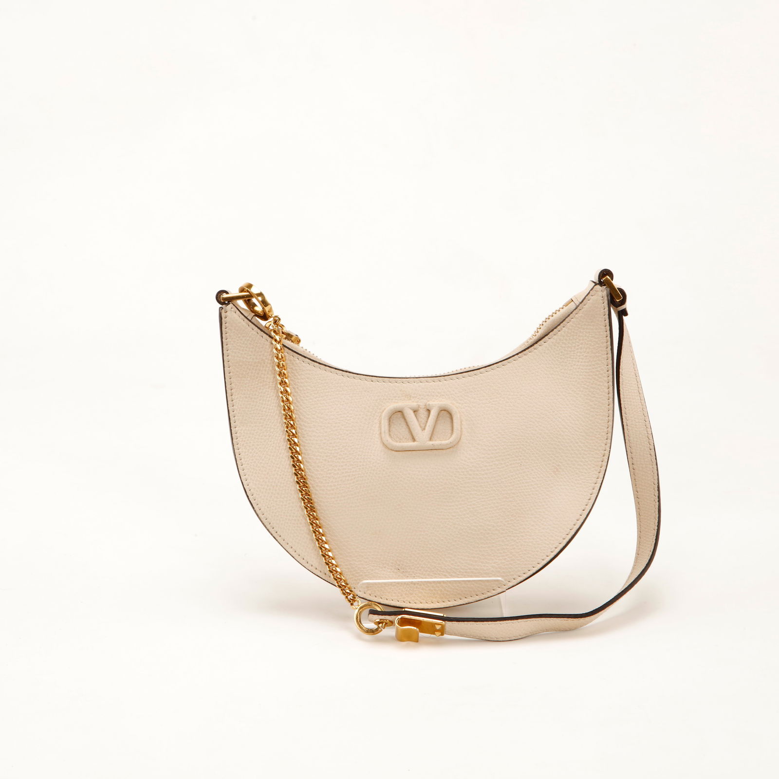 Valentino Garavani Mini Crescent Shoulder Bag: Chic and contemporary, this Valentino Garavani mini crescent shoulder bag is crafted in soft ivory grained leather featuring the signature tonal VLogo emblem elegantly centered on the front. The sculp