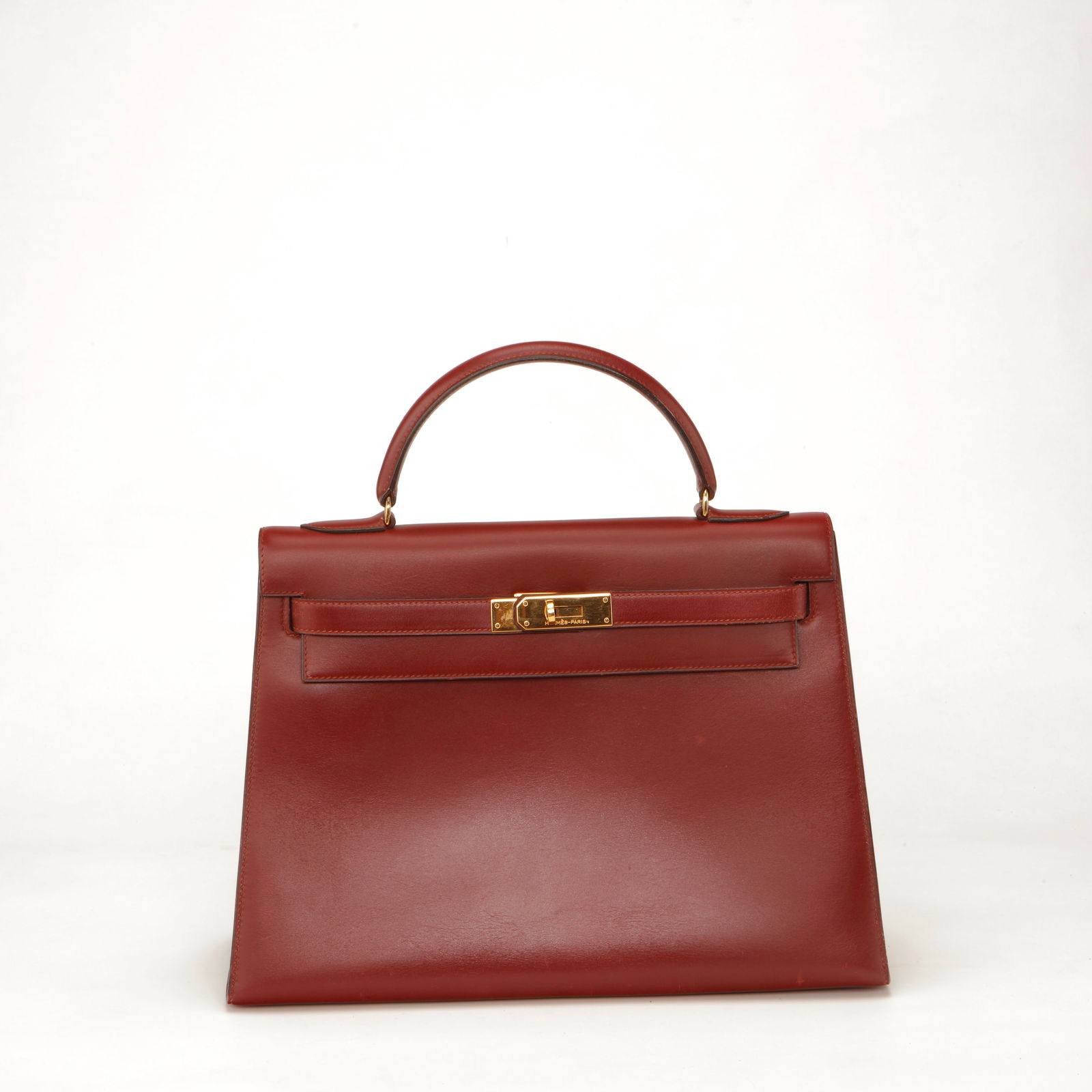 Hermès Kelly 32 Box Calf Leather Handbag – Rouge H with Gold Hardware: Authentic Hermès Kelly 32 crafted in classic Box Calf leather in the timeless Rouge H shade. Featuring a structured silhouette with a smooth, glossy finish, this elegant piece is accented with gold-p