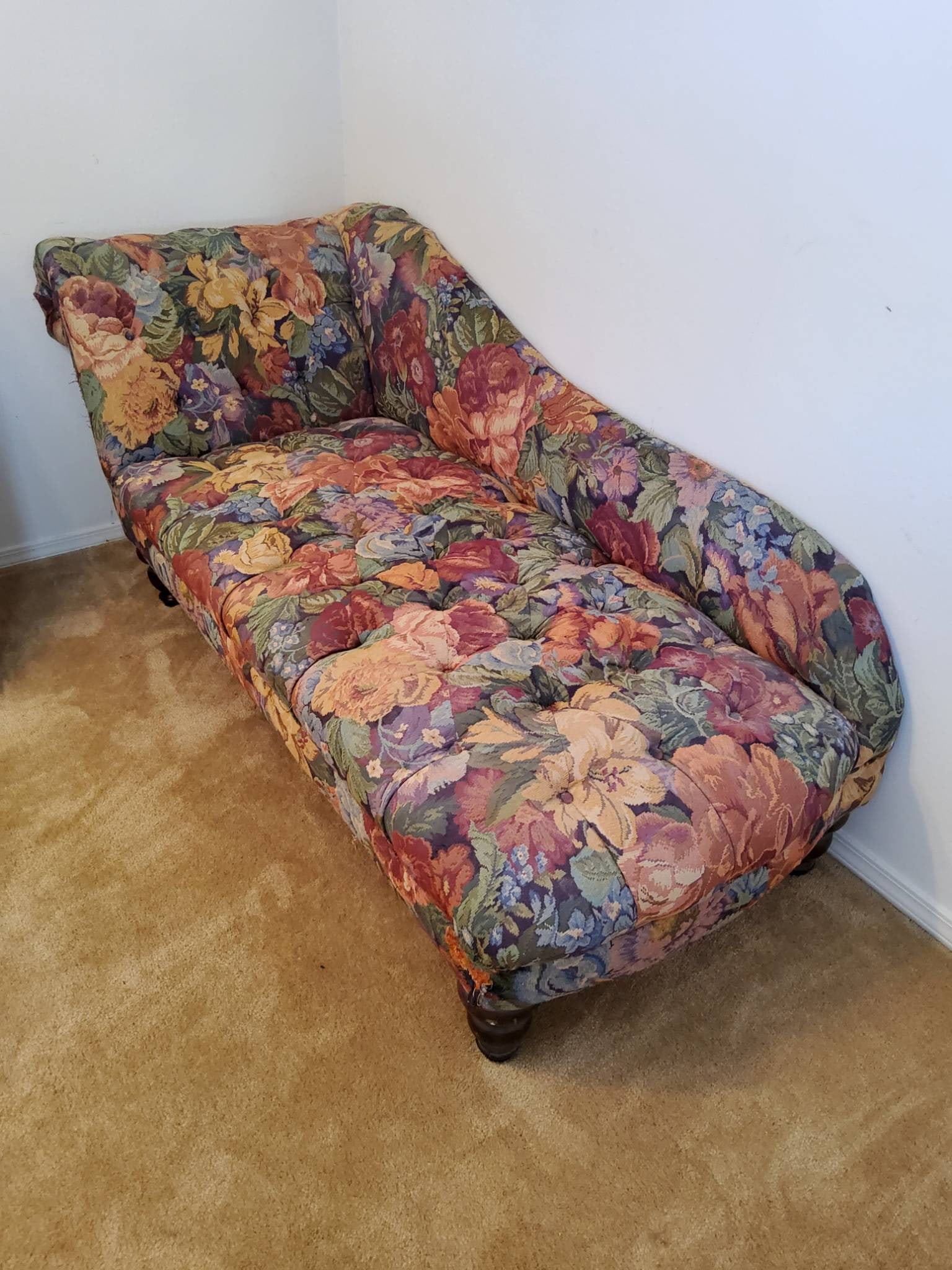 Floral Upholstered Chaise Lounge with Tufted Accents: Floral upholstered chaise lounge featuring a vibrant multicolor floral pattern on fabric. The piece includes tufted accents along the backrest and seat, with a rolled armrest design on one side. It re