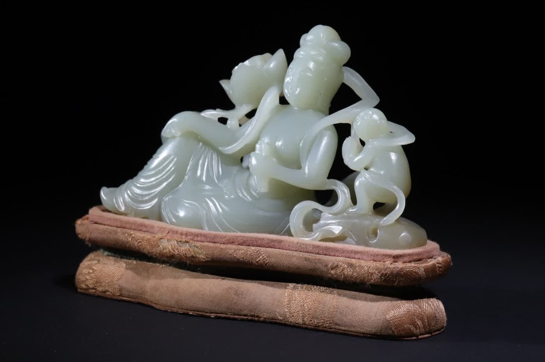 A Qing Dynasty Hetian jade boy worshiping Guanyin ornament: Hetian jade boy worships Guanyin ornament, this ornament is made of Hetian green and white jade seed material, the whole material is round carved, the whole body is transparent and flawless, Guanyin i