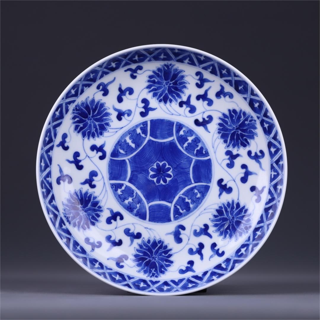 A blue and white entwined plate from the Qing Dynasty: The blue and white intertwined pattern plate of the Qing Dynasty is painted with intertwined lotus flowers in the center, the outer wall is decorated with dense intertwined flowers, the layout is full