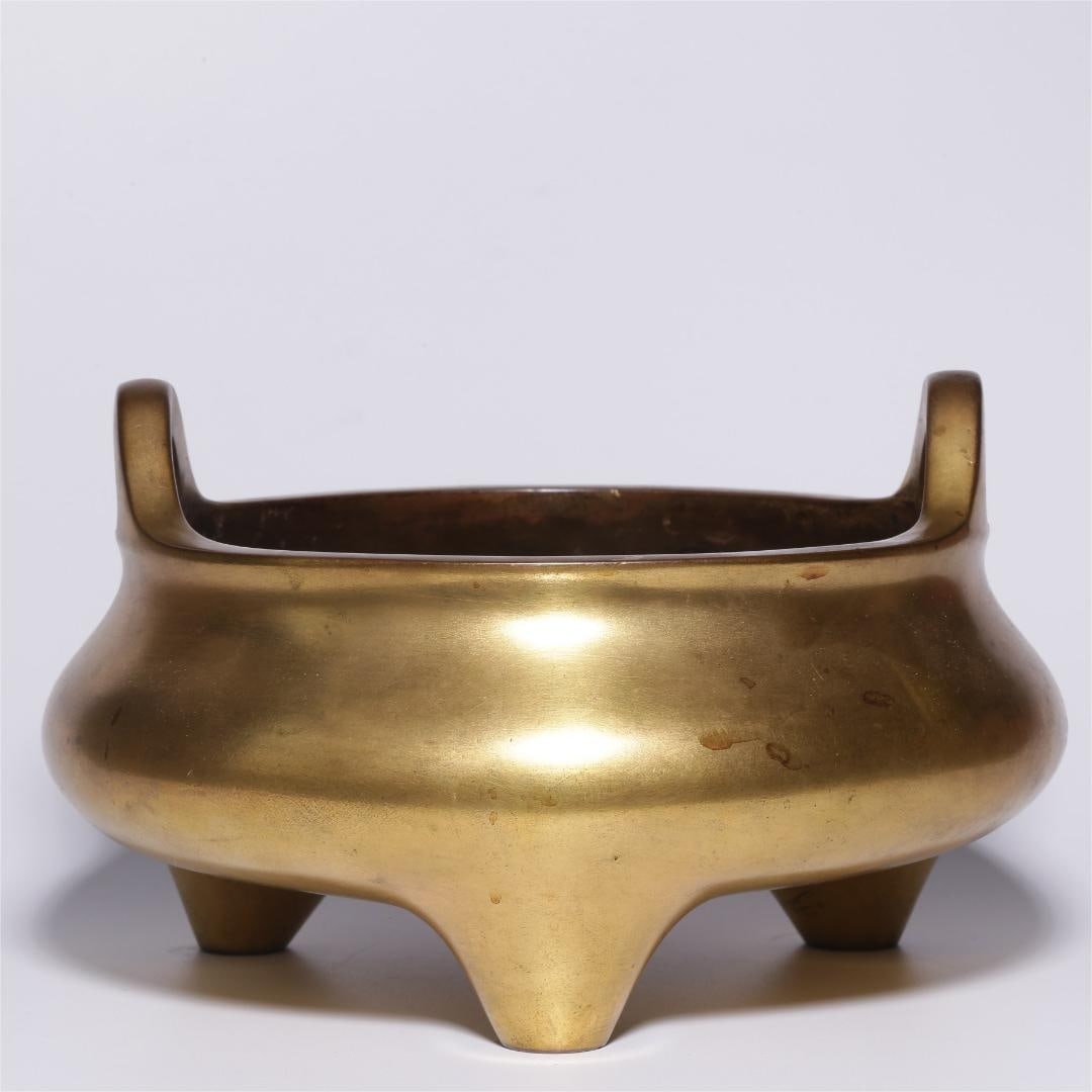 A copper gilt three-legged bridge ear furnace made in the Qianlong period of the Qing Dynasty: Qing Dynasty Qianlong year copper gilt three-legged bridge ear furnace Size:H:11.5cmD:20cmW:3.481kg (The Dimensions Of All Batches Are Manually Measured.If You Need More Detailed Information, Please C