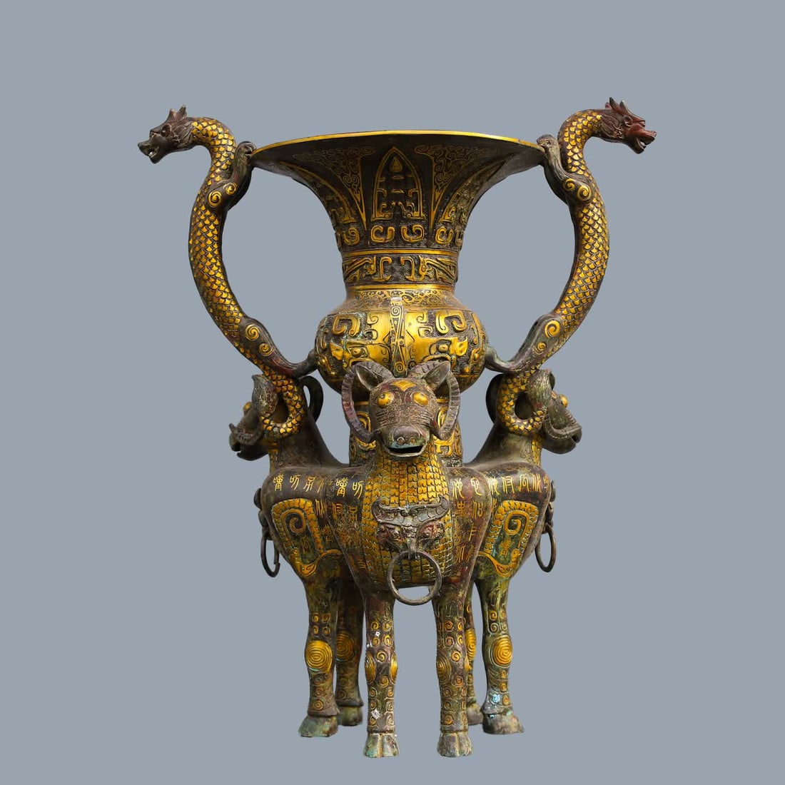 A Han Dynasty bronze Cuojin Shuanglong Three Sheep Zun: Han Dynasty Bronze Cuojin Shuanglong Three Sheep Zun SIZE: W:13.9kg L:52cm H:64cm (The Dimensions Of All Batches Are Manually Measured.If You Need More Detailed Information, Please Contact Our Custome