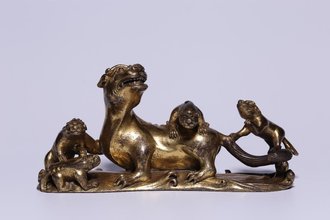 A Qing Dynasty copper-gilt Taishi Young Lion paperweight: Qing Dynasty copper gilt Taishi Young Lion paperweight This paperweight is gilded all over the body, and the copper is thick and heavy, which is refined. The lion looks back, the mane is smooth, the e